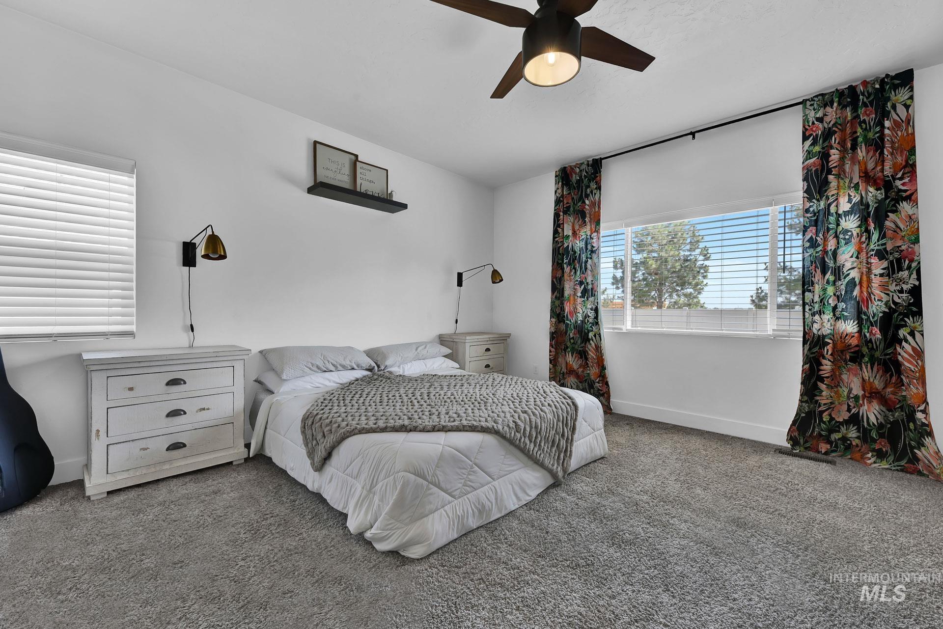 Carpeted bedroom featuring ceiling fan and baseboards