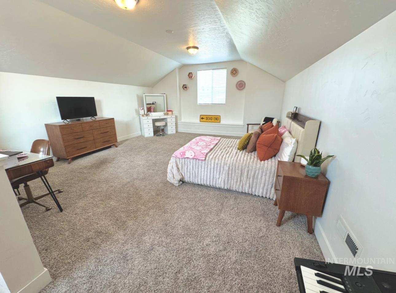 Bedroom with carpet, a textured ceiling, and vaulted ceiling