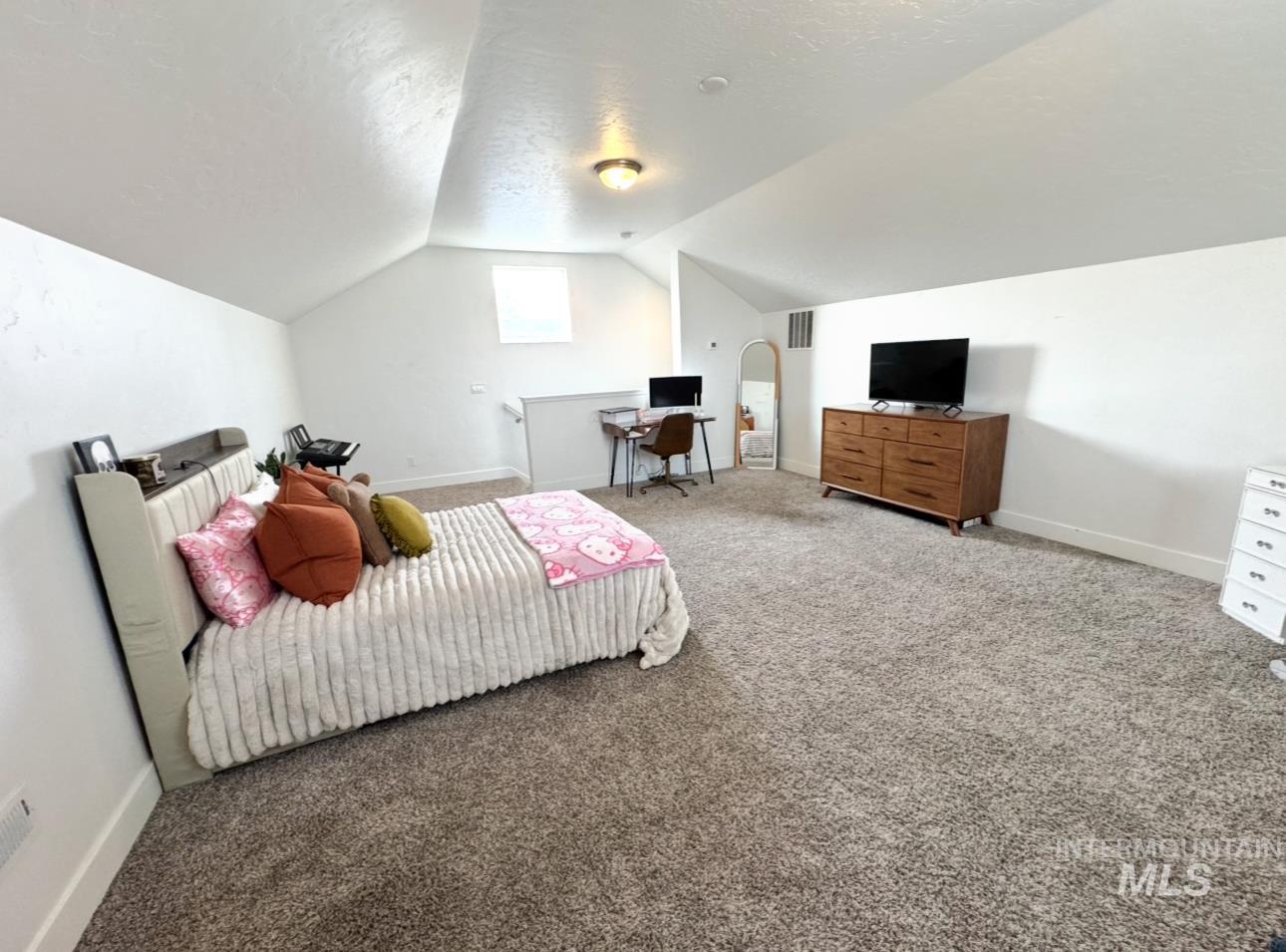 Bedroom featuring light colored carpet, a textured ceiling, and lofted ceiling