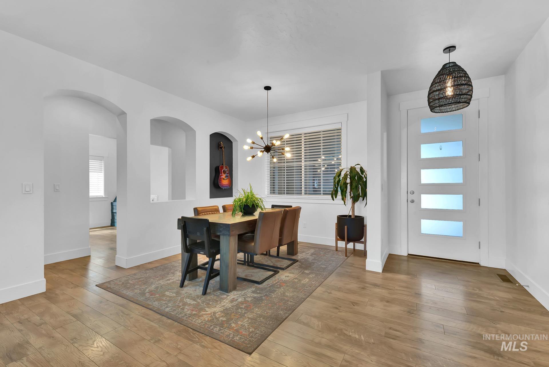 Dining room with a chandelier, light wood-style flooring, and arched walkways