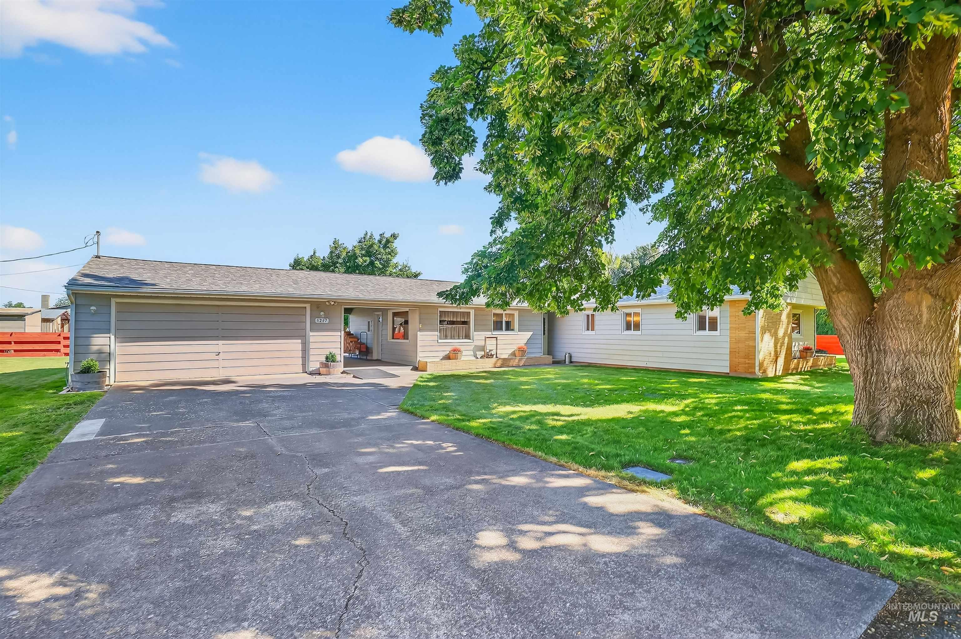 Ranch-style house with driveway, an attached garage, a front yard, and roof with shingles