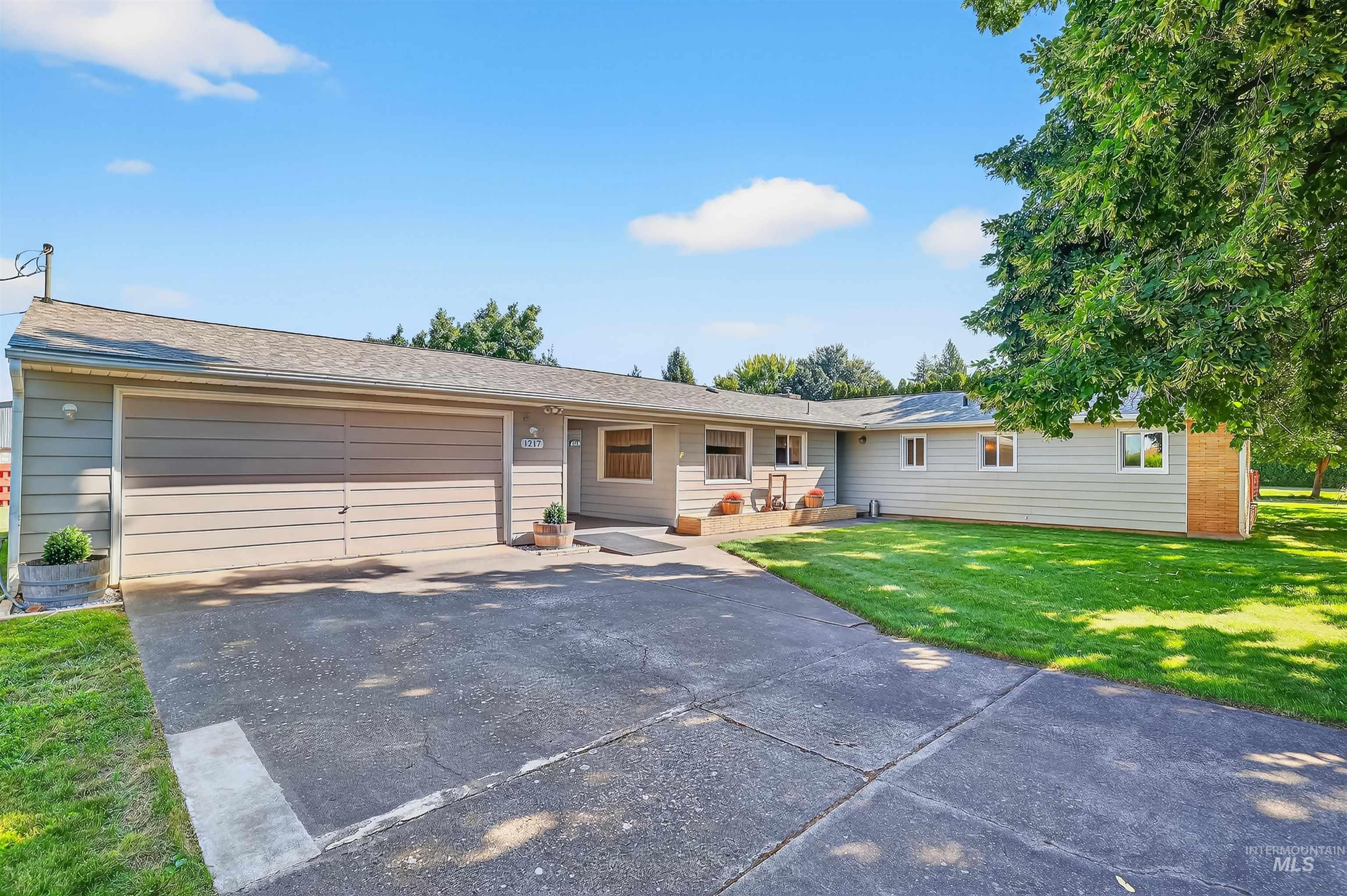 Single story home featuring driveway, a front yard, an attached garage, and a shingled roof
