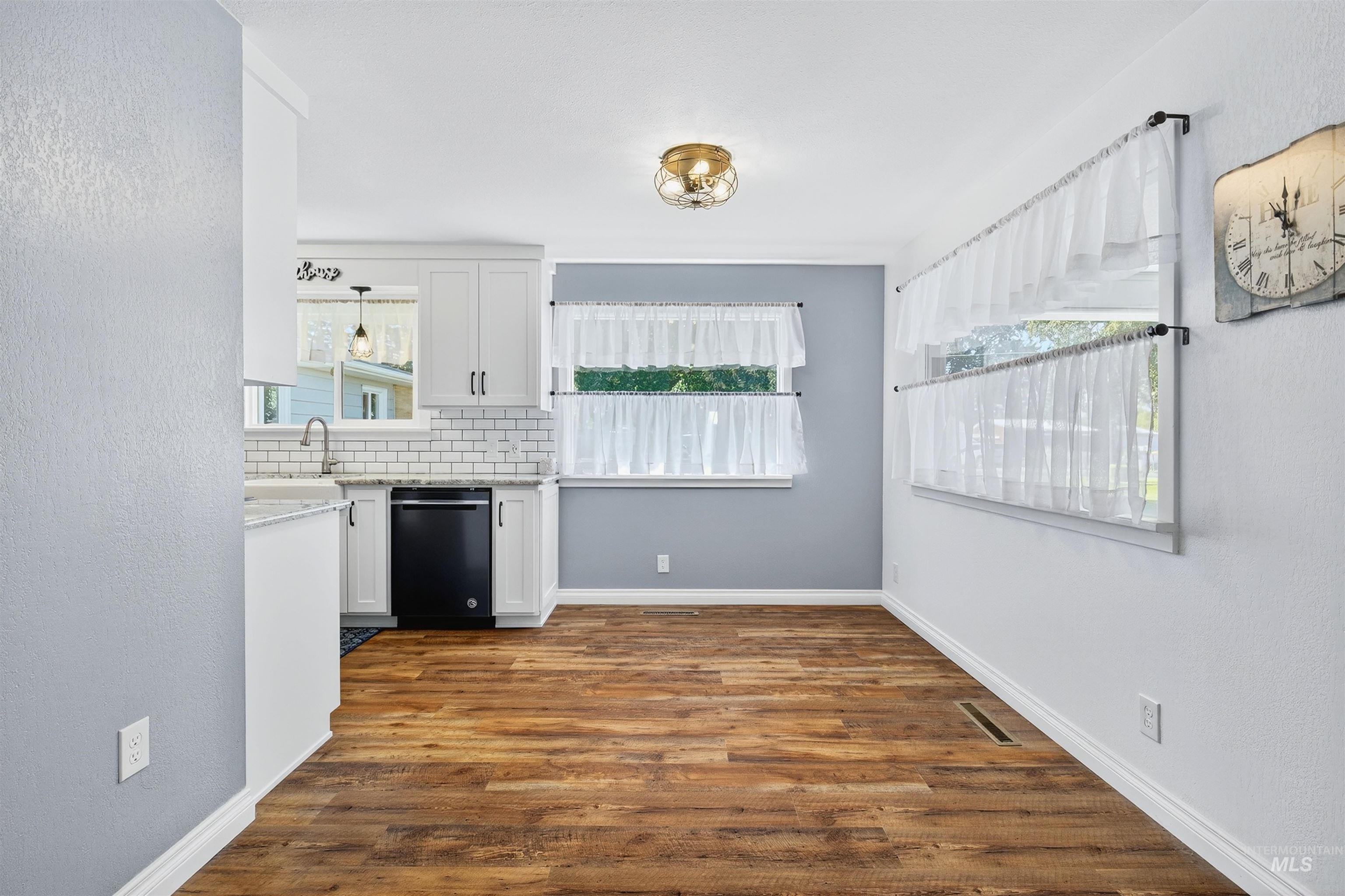 Kitchen with a textured wall, white cabinetry, healthy amount of natural light, dark wood finished floors, and black dishwasher