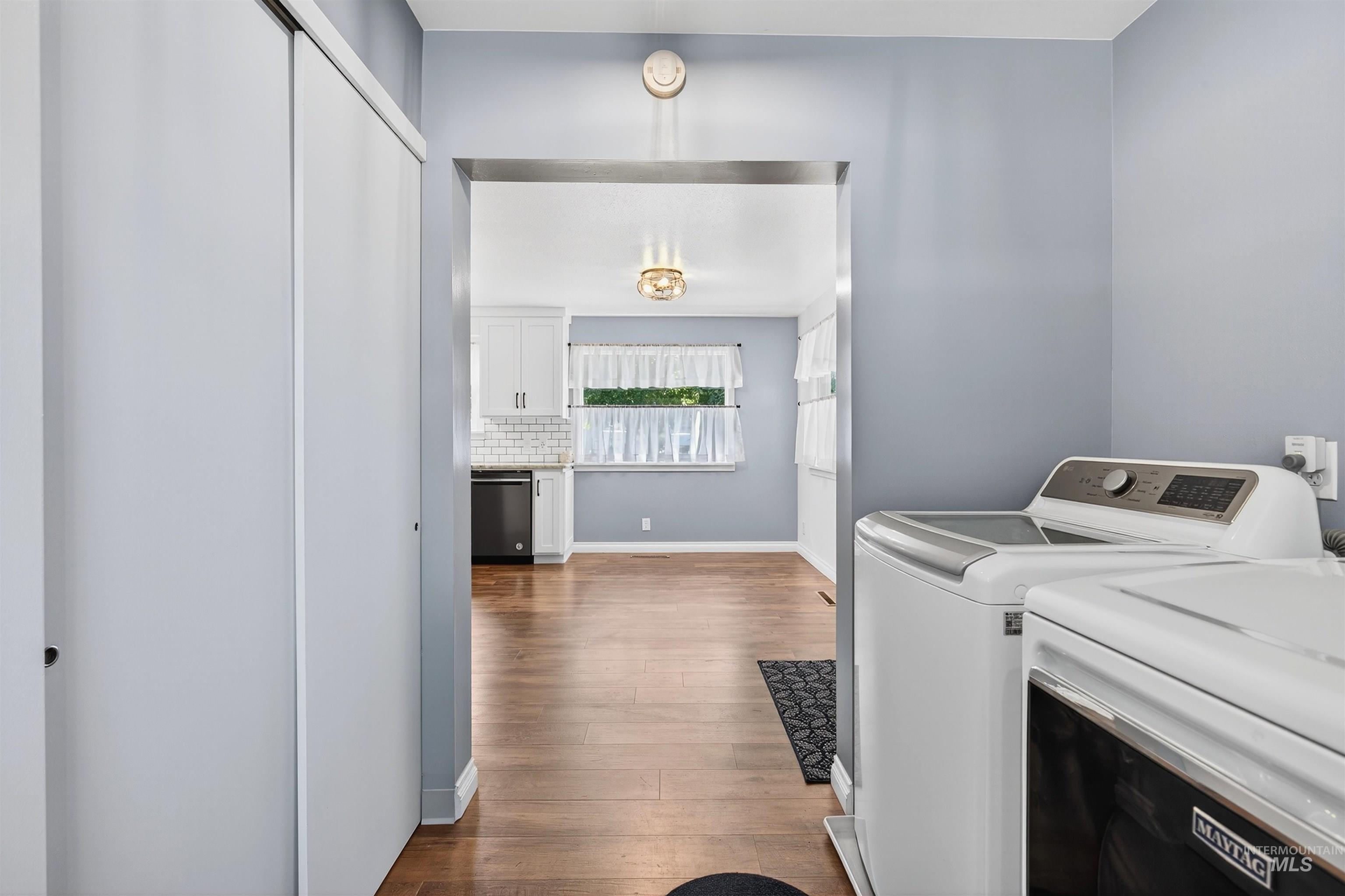 Laundry area with light wood-style floors and washer and clothes dryer