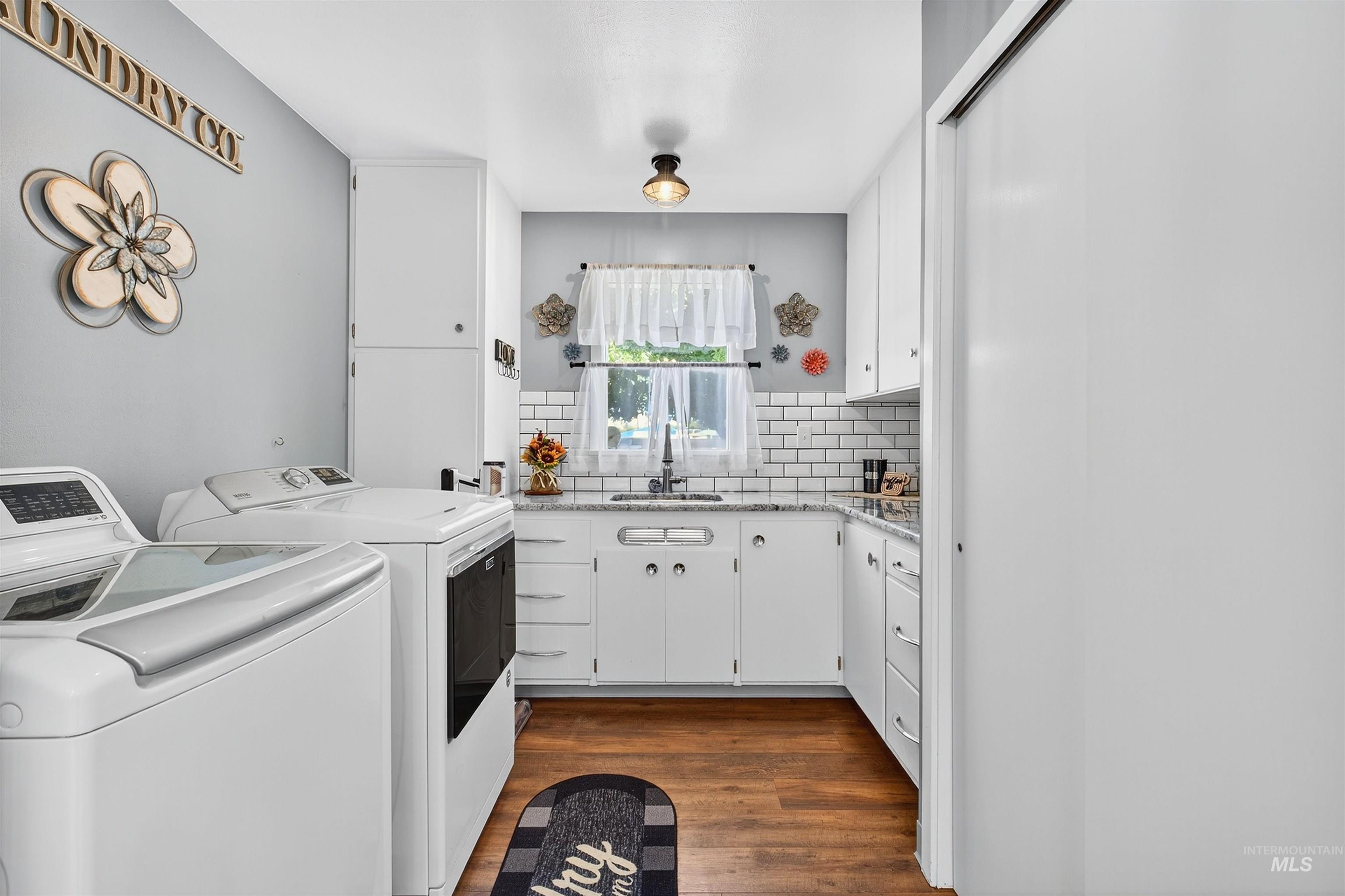Laundry room featuring dark wood-type flooring, washer and clothes dryer, and cabinet space