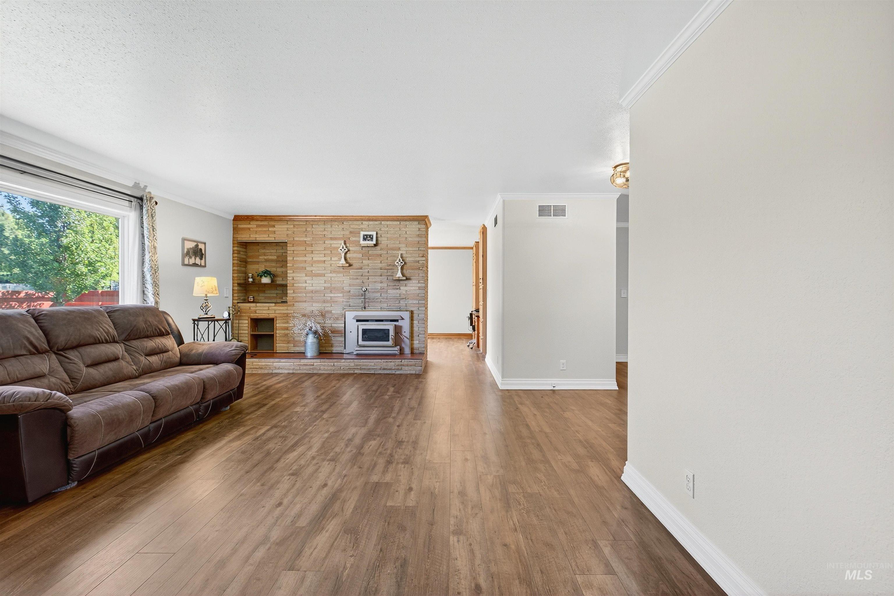 Living area with wood finished floors, crown molding, and a large fireplace