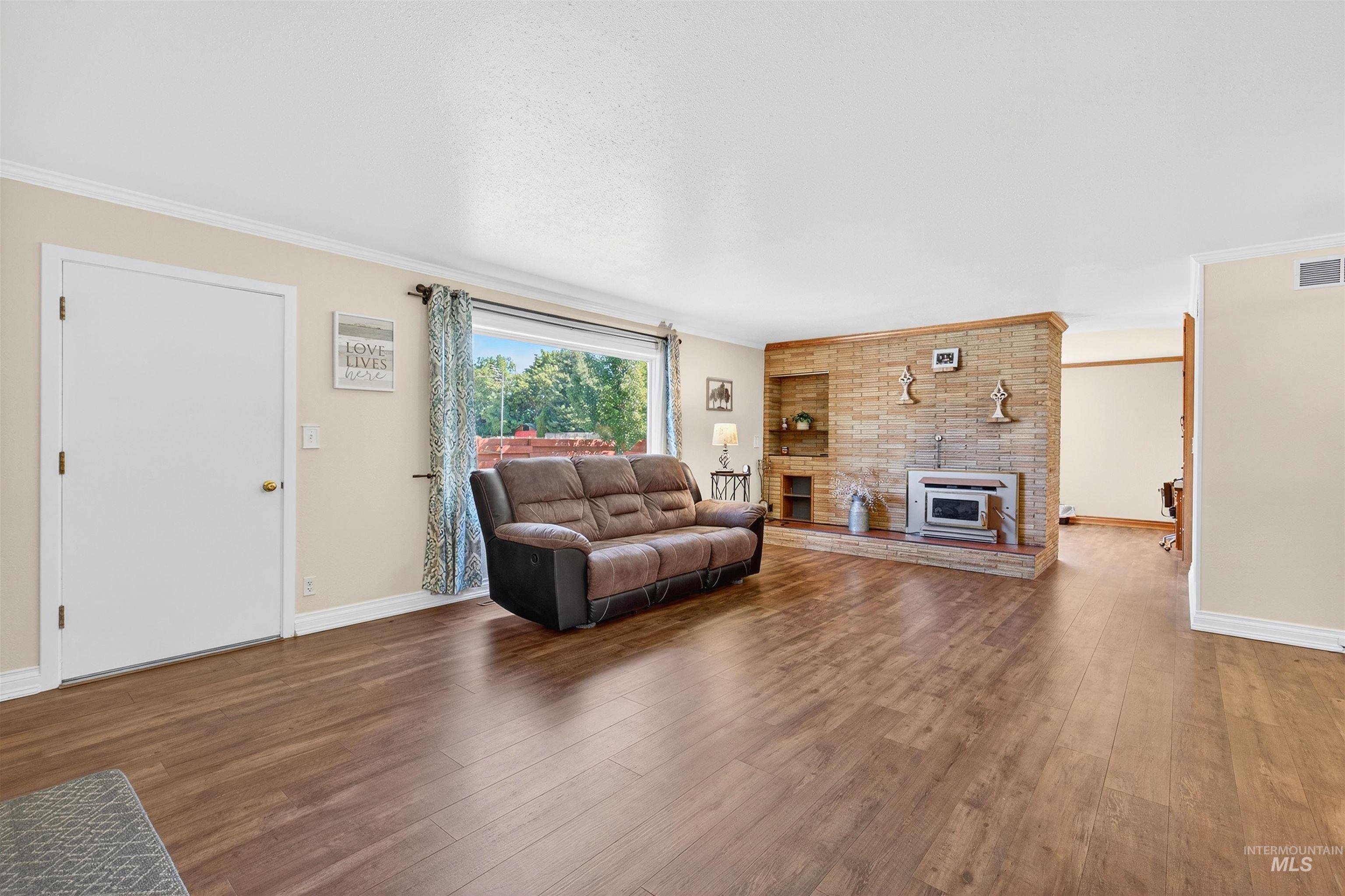 Living room featuring crown molding, wood finished floors, and a fireplace