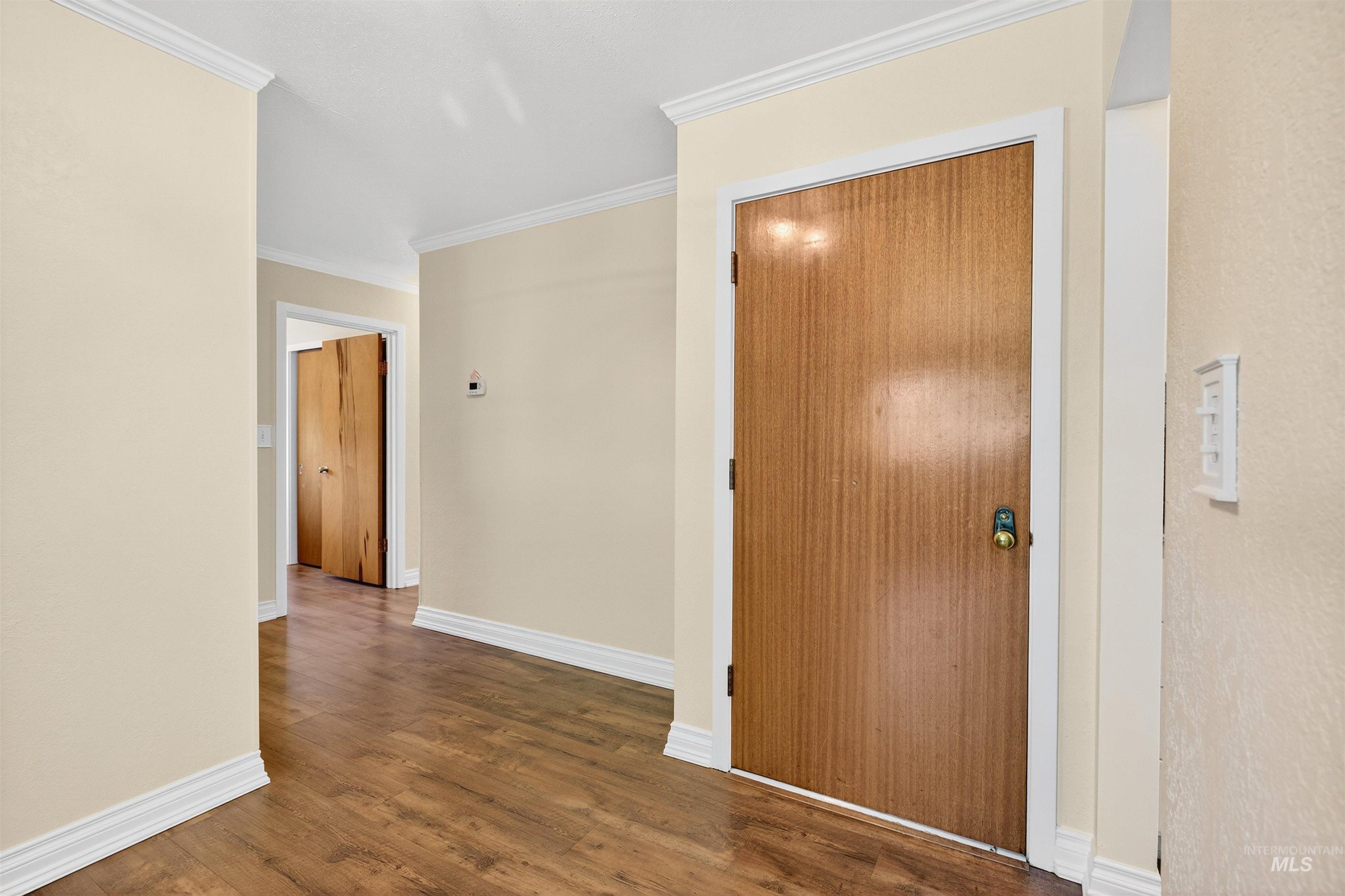 Hallway with dark wood-style floors and ornamental molding
