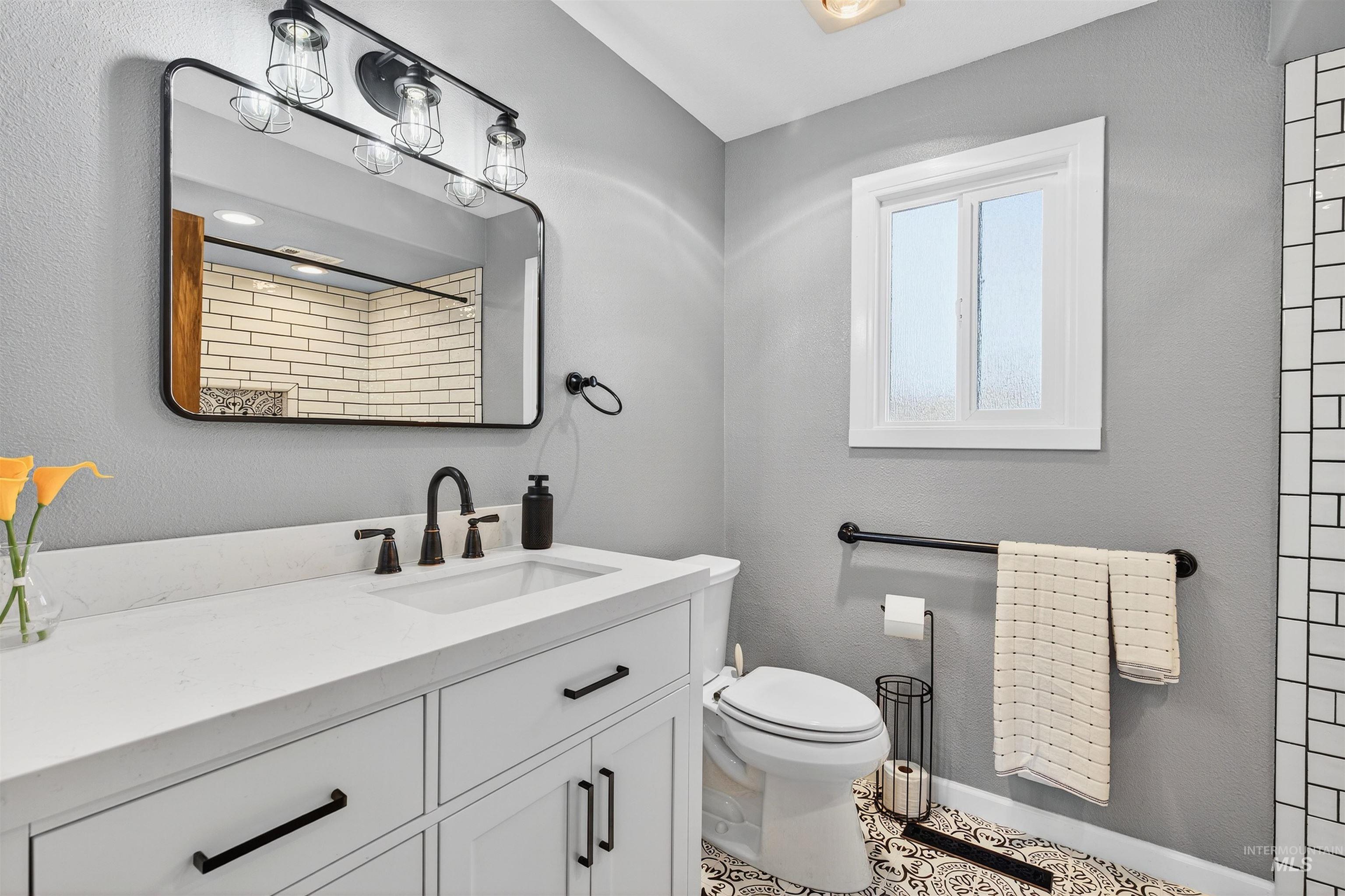 Full bathroom with vanity, a textured wall, and tile patterned flooring
