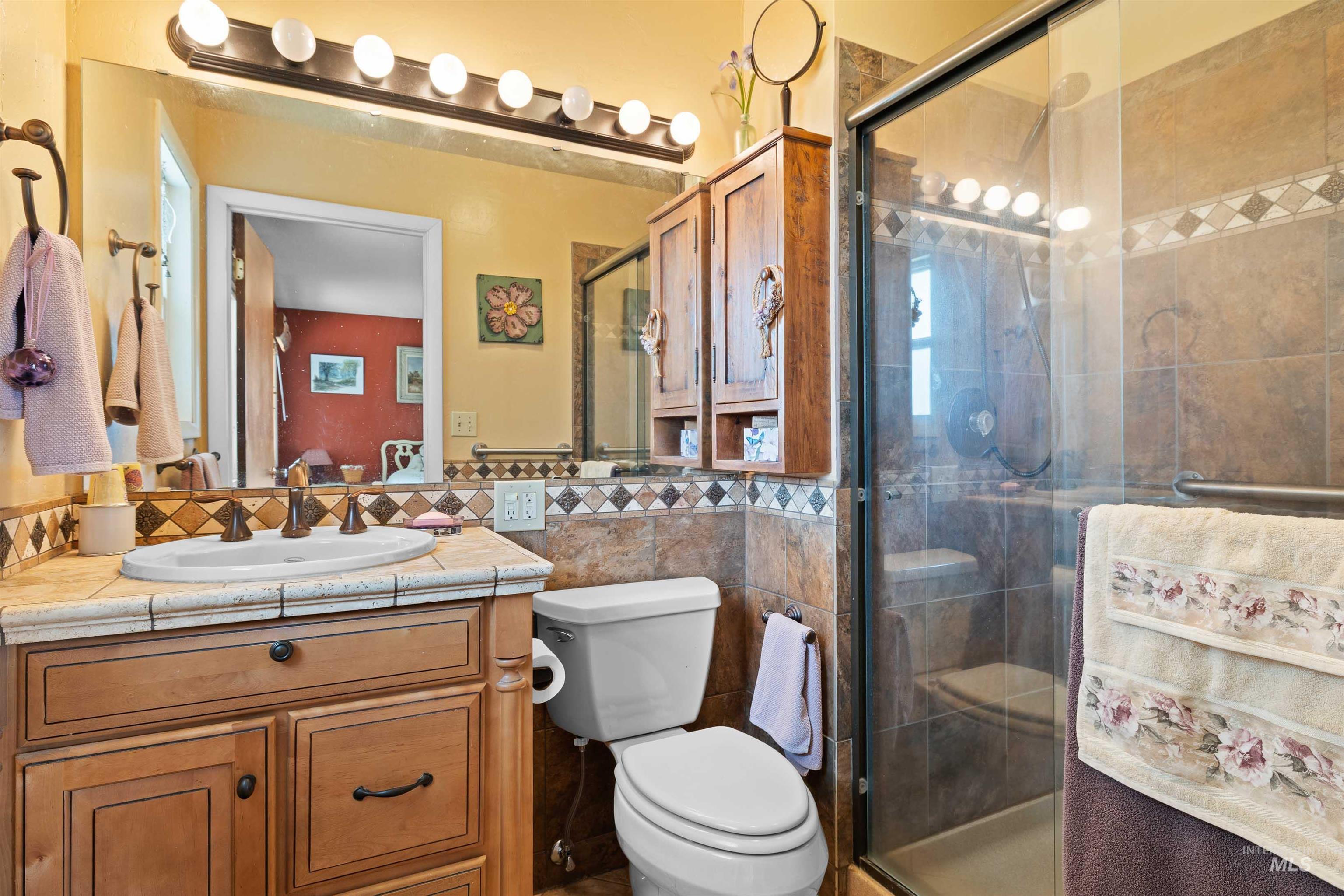 Full bathroom with vanity, a shower stall, and tile walls