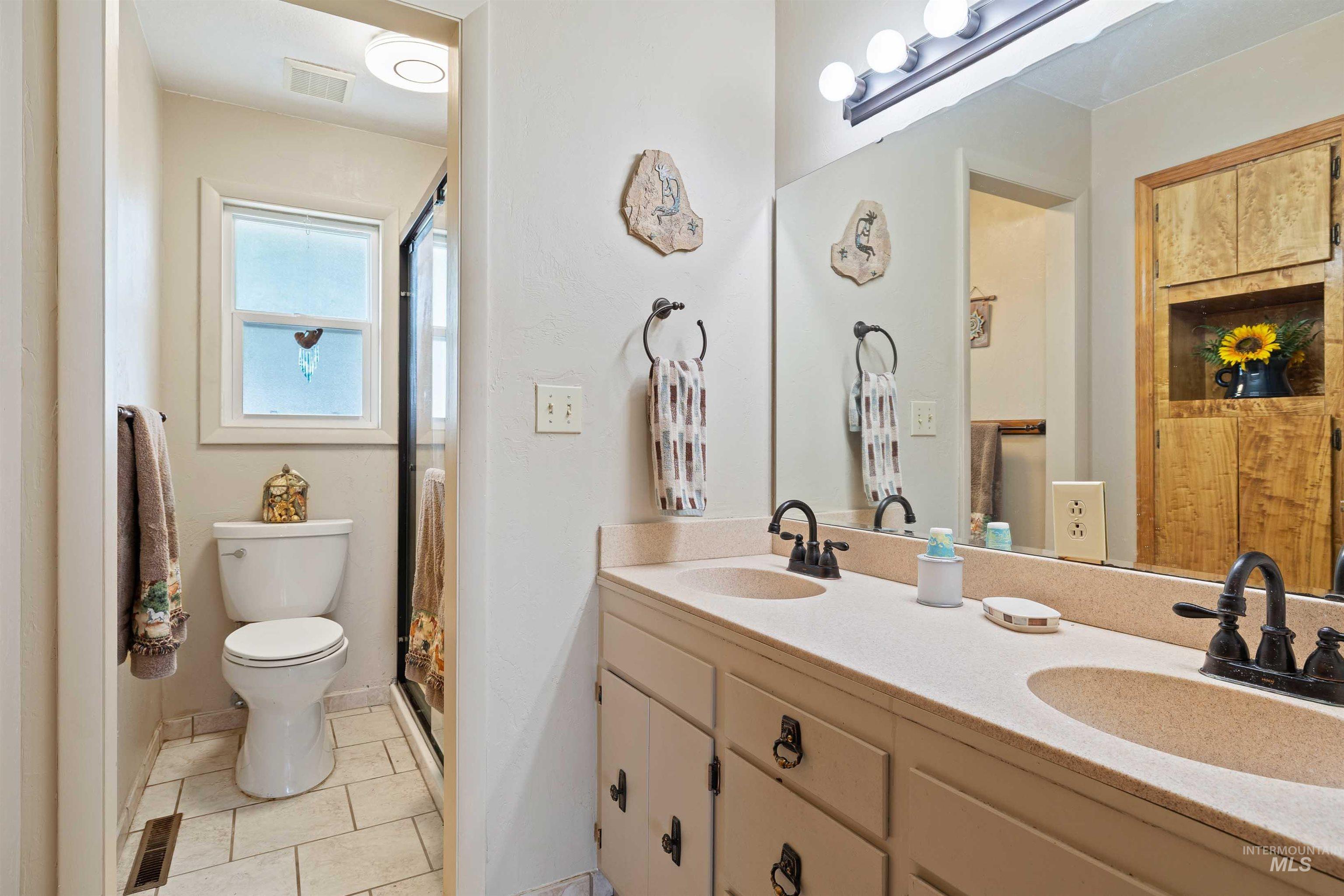 Full bath featuring light tile patterned floors, double vanity, and a shower
