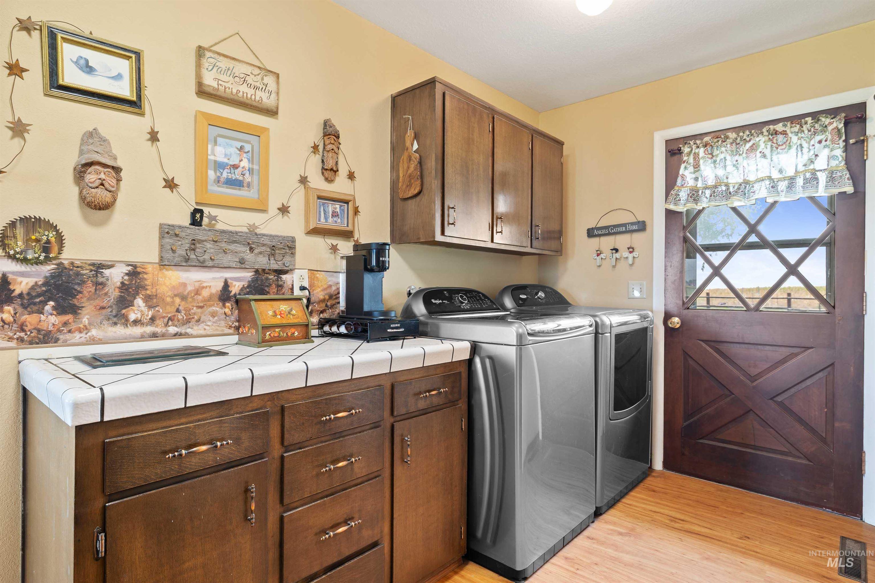 Laundry area with light wood-type flooring, cabinet space, and washer and dryer