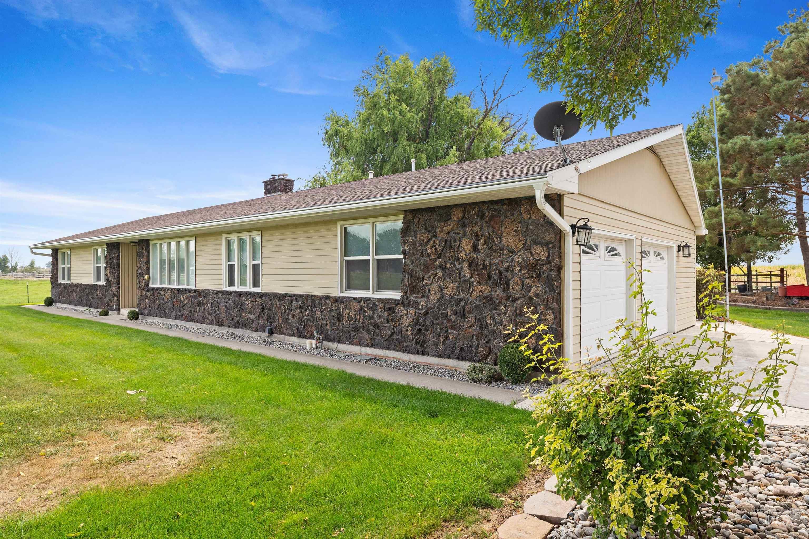 View of front of home featuring stone siding, a chimney, and a front lawn