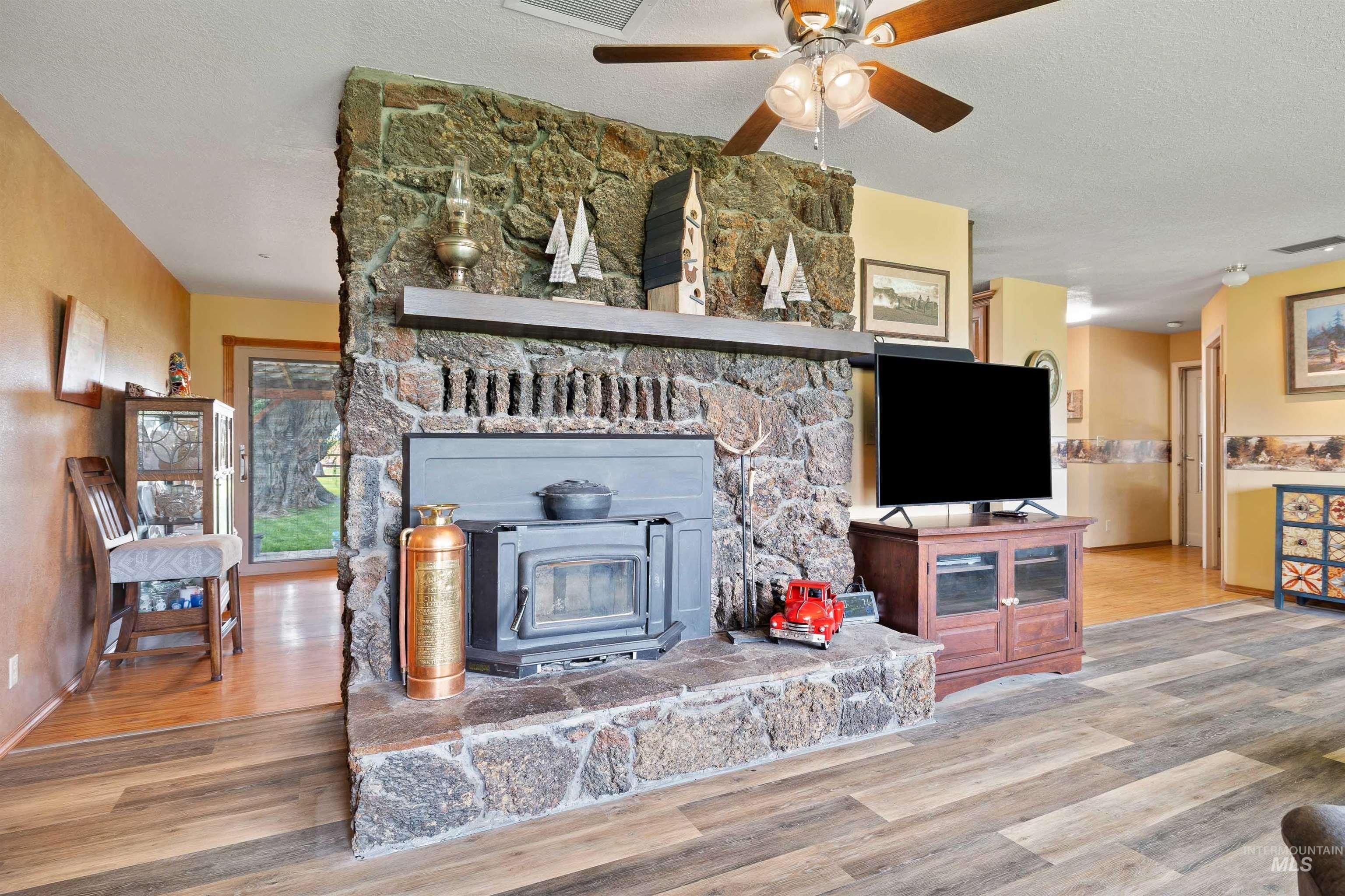 Living area with a textured ceiling, wood finished floors, and ceiling fan