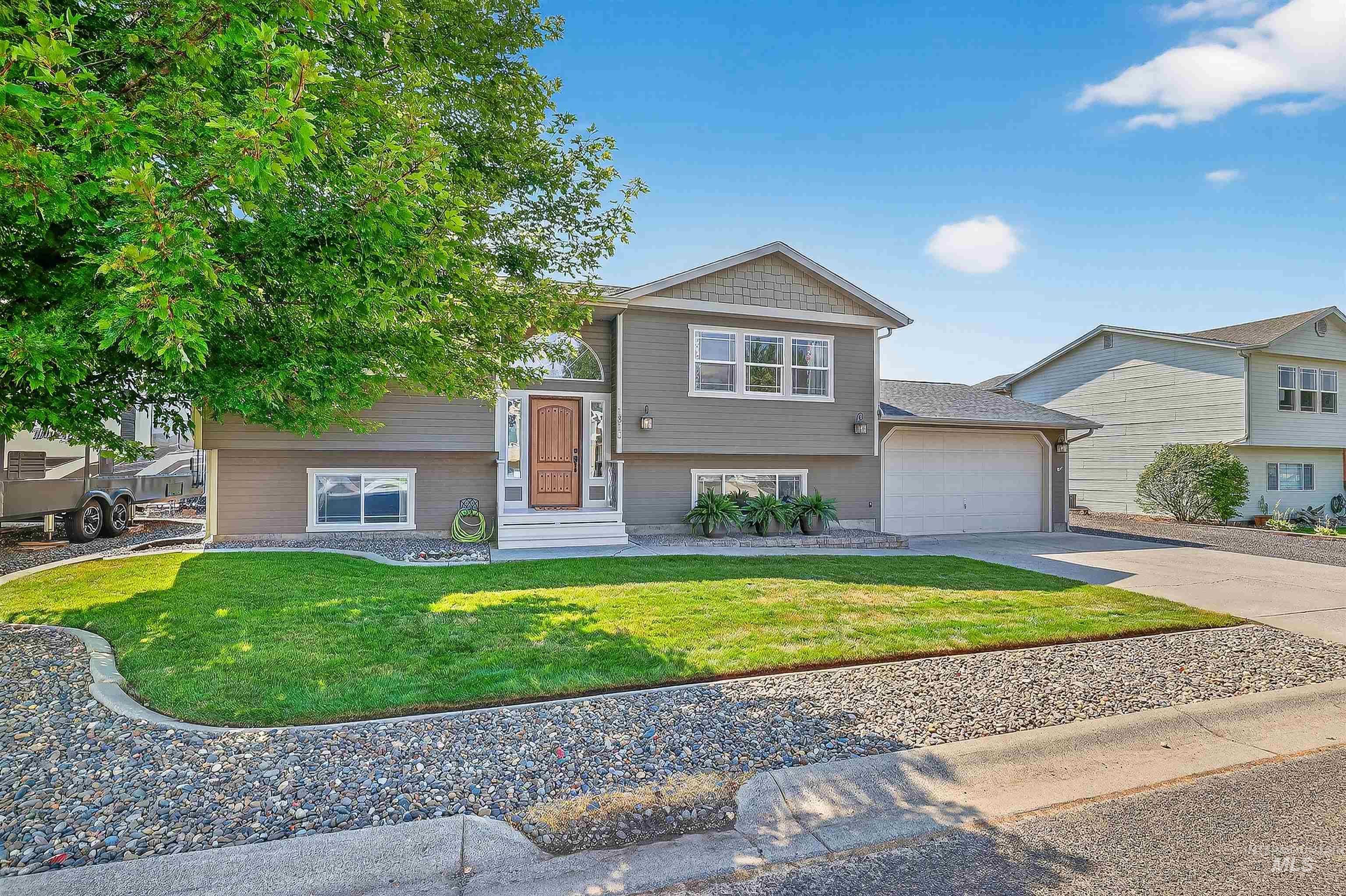Bi-level home with concrete driveway, a front lawn, and a garage