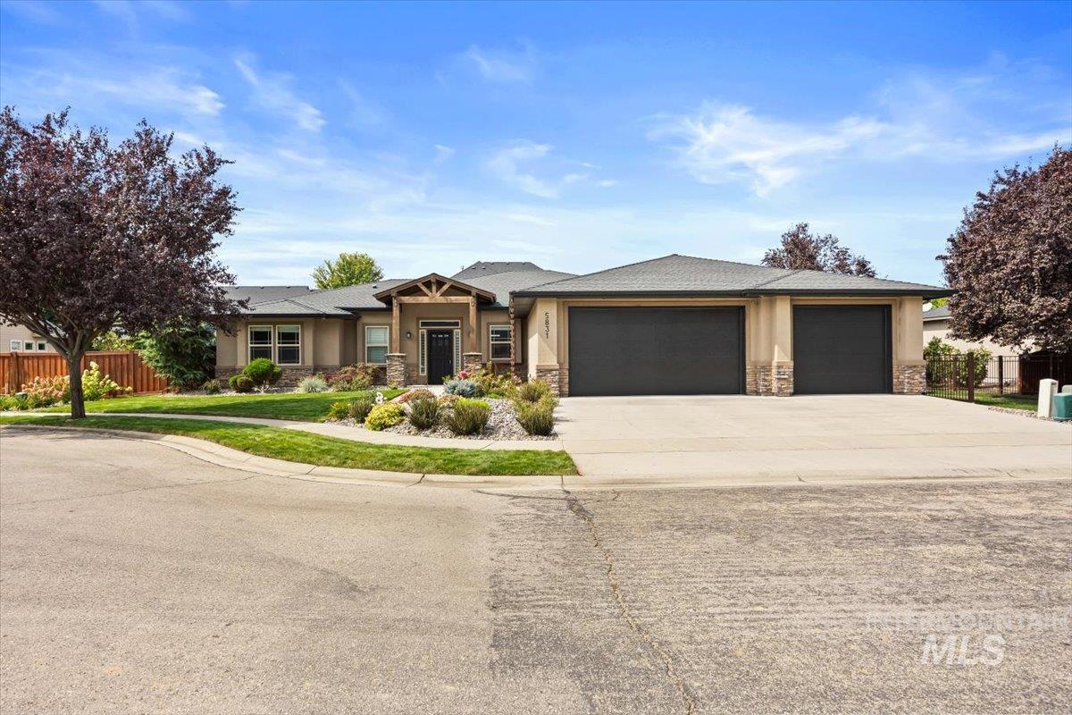 View of front of house with stone siding, driveway, a garage, and stucco siding