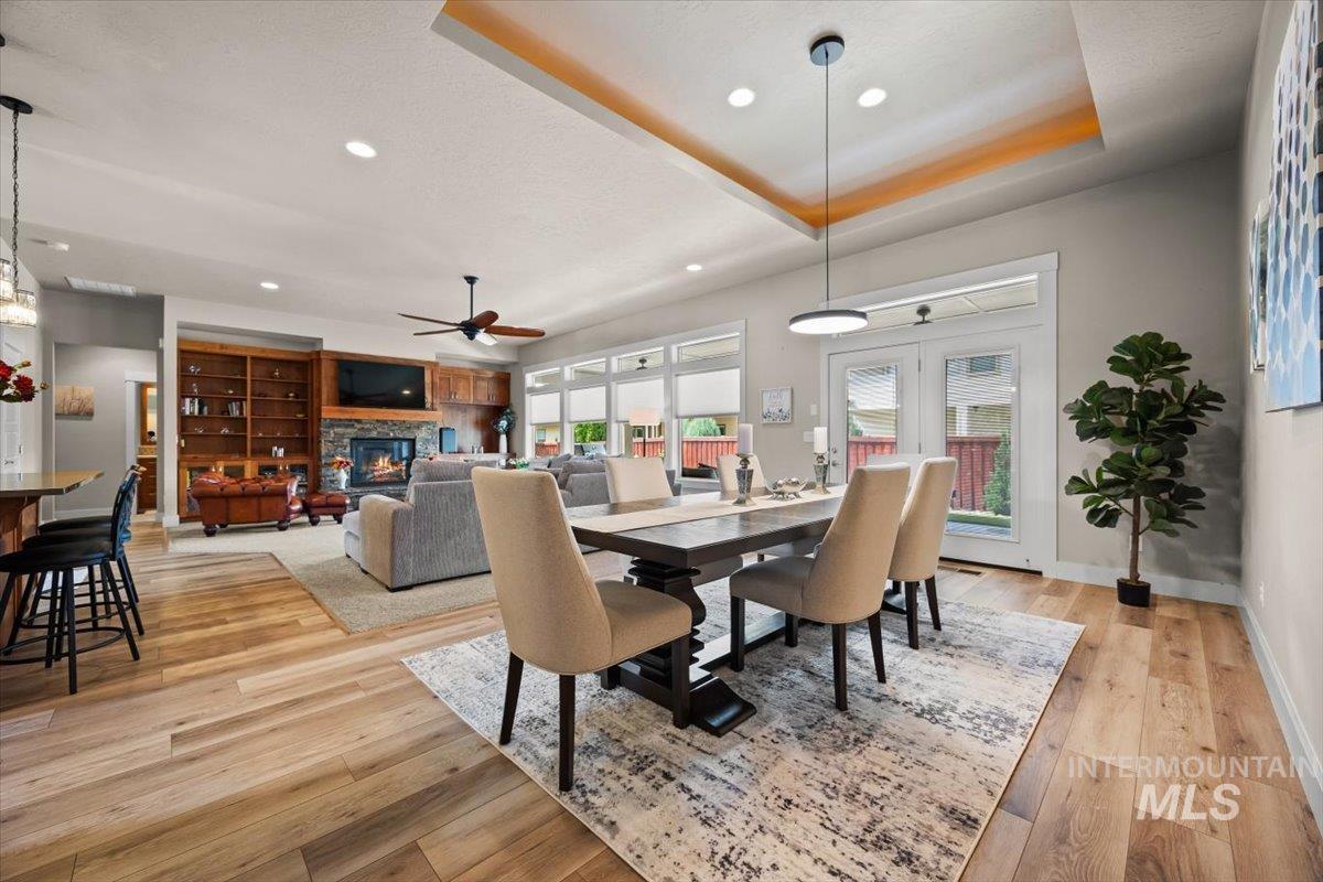 Dining area featuring a fireplace, recessed lighting, a tray ceiling, light wood finished floors, and ceiling fan