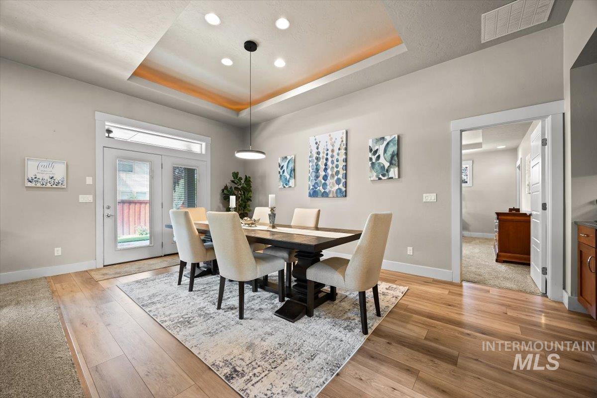 Dining room with a tray ceiling, light wood-style floors, recessed lighting, and a textured ceiling