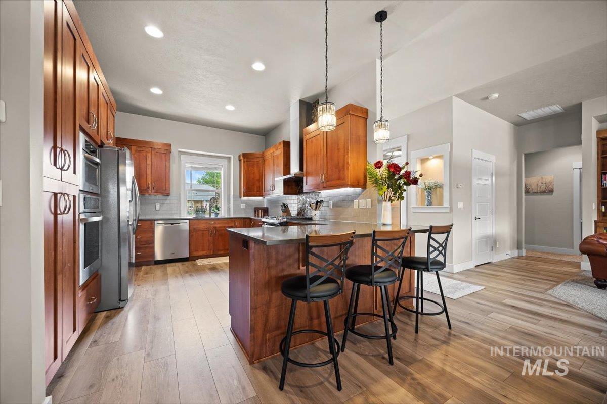 Kitchen with brown cabinets, tasteful backsplash, a peninsula, light wood-type flooring, and recessed lighting