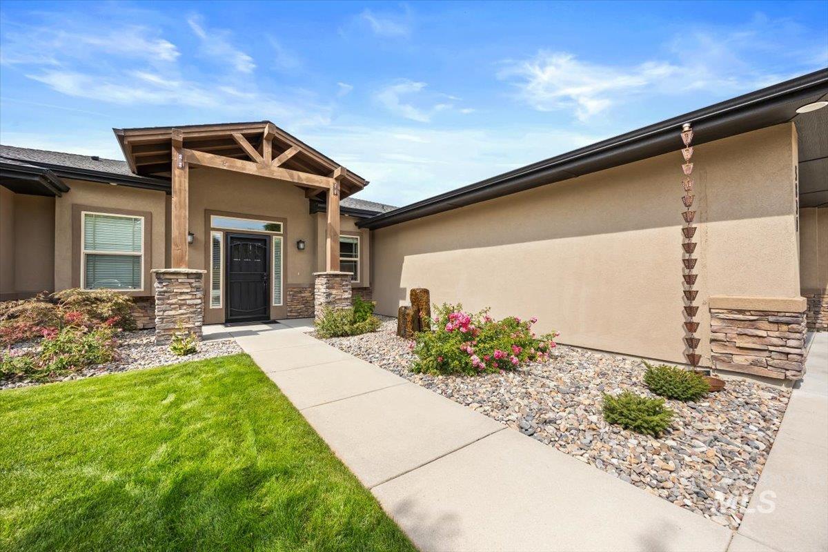 Property entrance featuring stone siding, stucco siding, and a yard