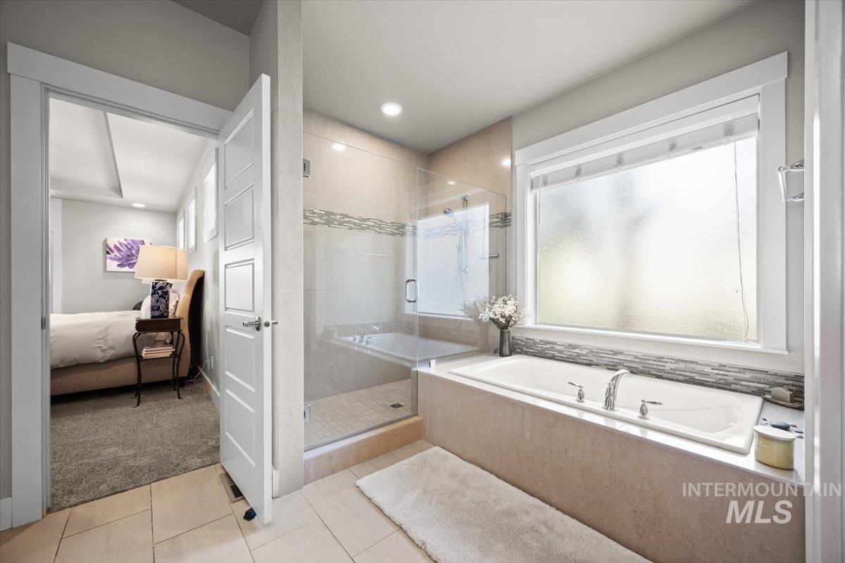 Ensuite bathroom with a stall shower, a bath, light tile patterned floors, and recessed lighting