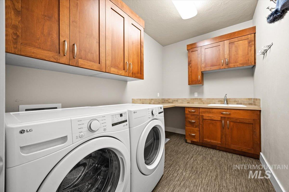 Laundry area featuring independent washer and dryer, cabinet space, and a textured ceiling