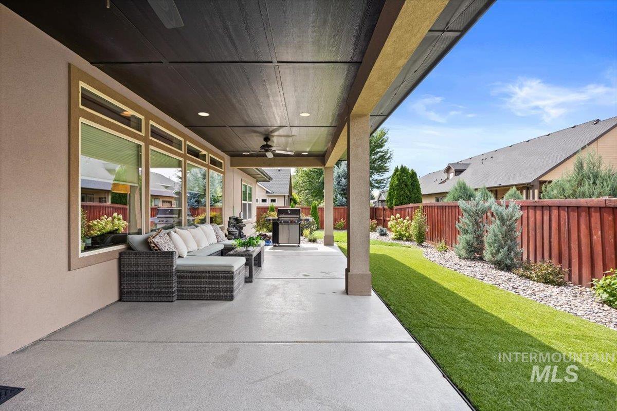 Fenced backyard with an outdoor living space, a patio area, a ceiling fan, and a grill