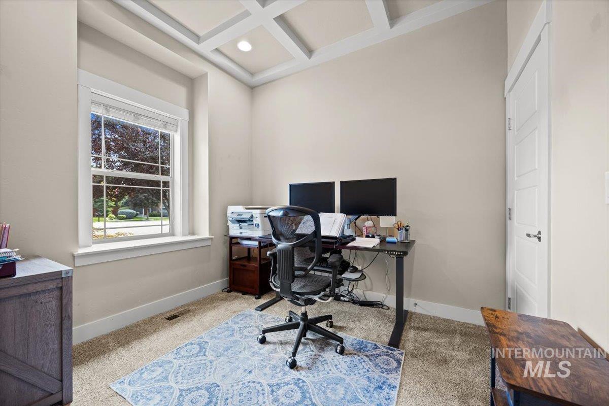 Home office featuring coffered ceiling, light carpet, and beamed ceiling