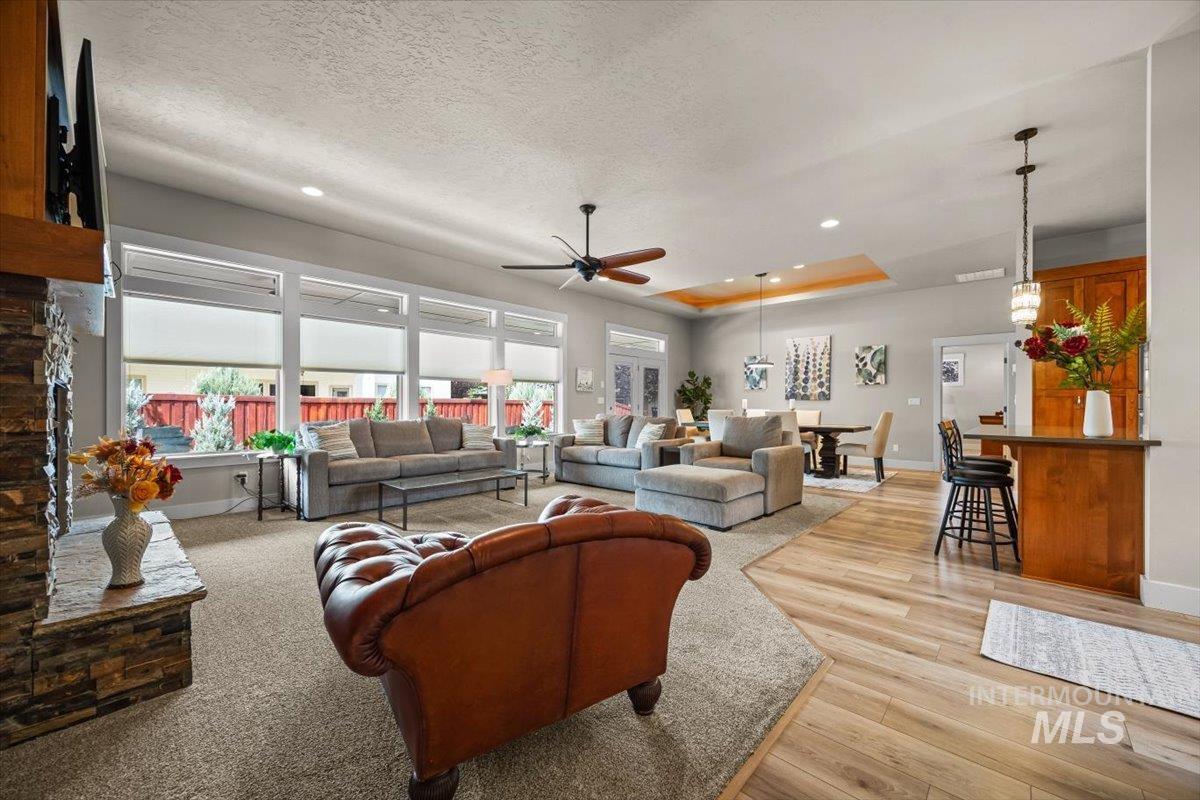 Living area with a tray ceiling, recessed lighting, a ceiling fan, light wood-style floors, and a textured ceiling