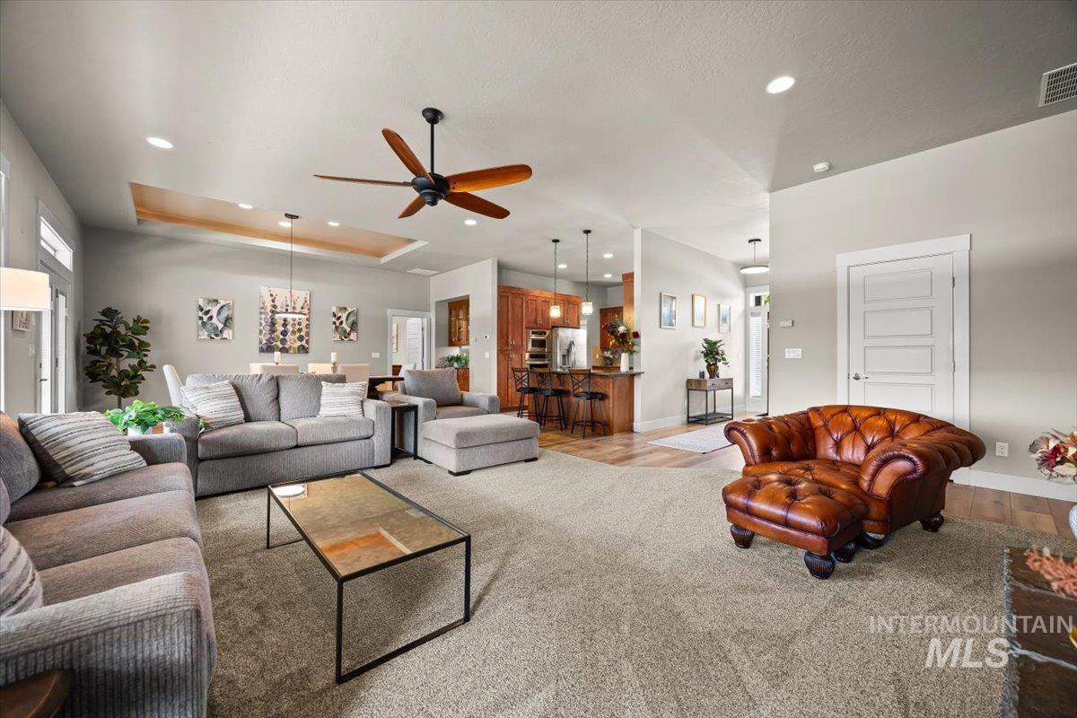 Living room with a tray ceiling, recessed lighting, light wood-type flooring, and ceiling fan