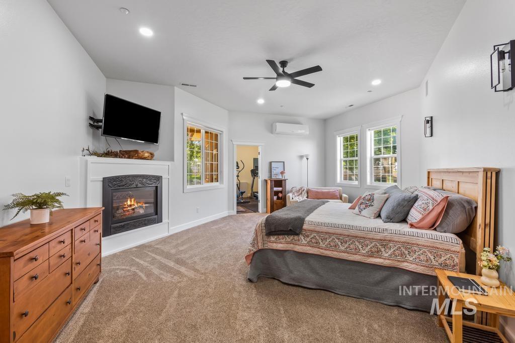 Bedroom featuring a glass covered fireplace, carpet, a ceiling fan, and recessed lighting
