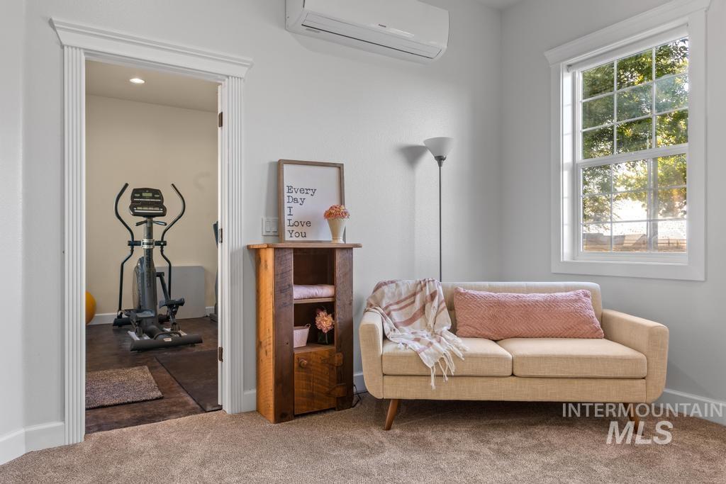 Living area with a wall mounted air conditioner and carpet flooring