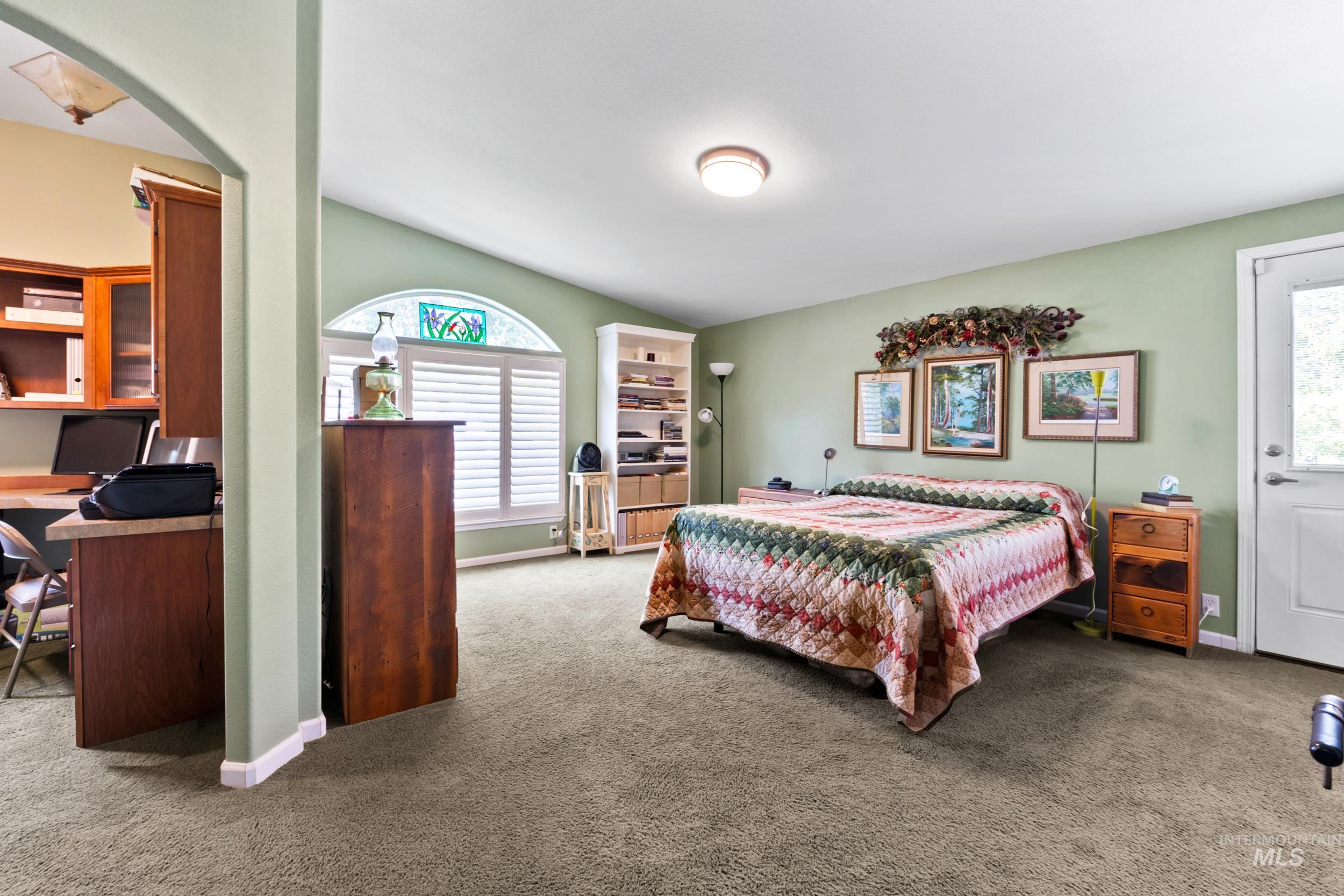 Bedroom with an office area, carpet, and arched walkways