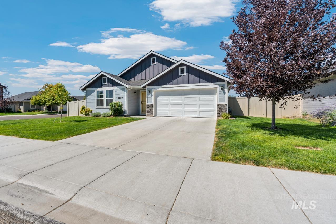 View of front  featuring board and batten siding, an attached garage, stone siding, and concrete driveway