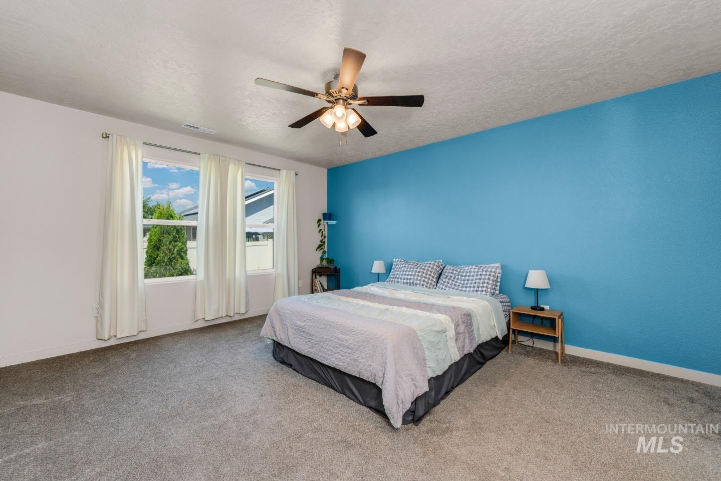 Carpeted bedroom featuring ceiling fan and a textured ceiling