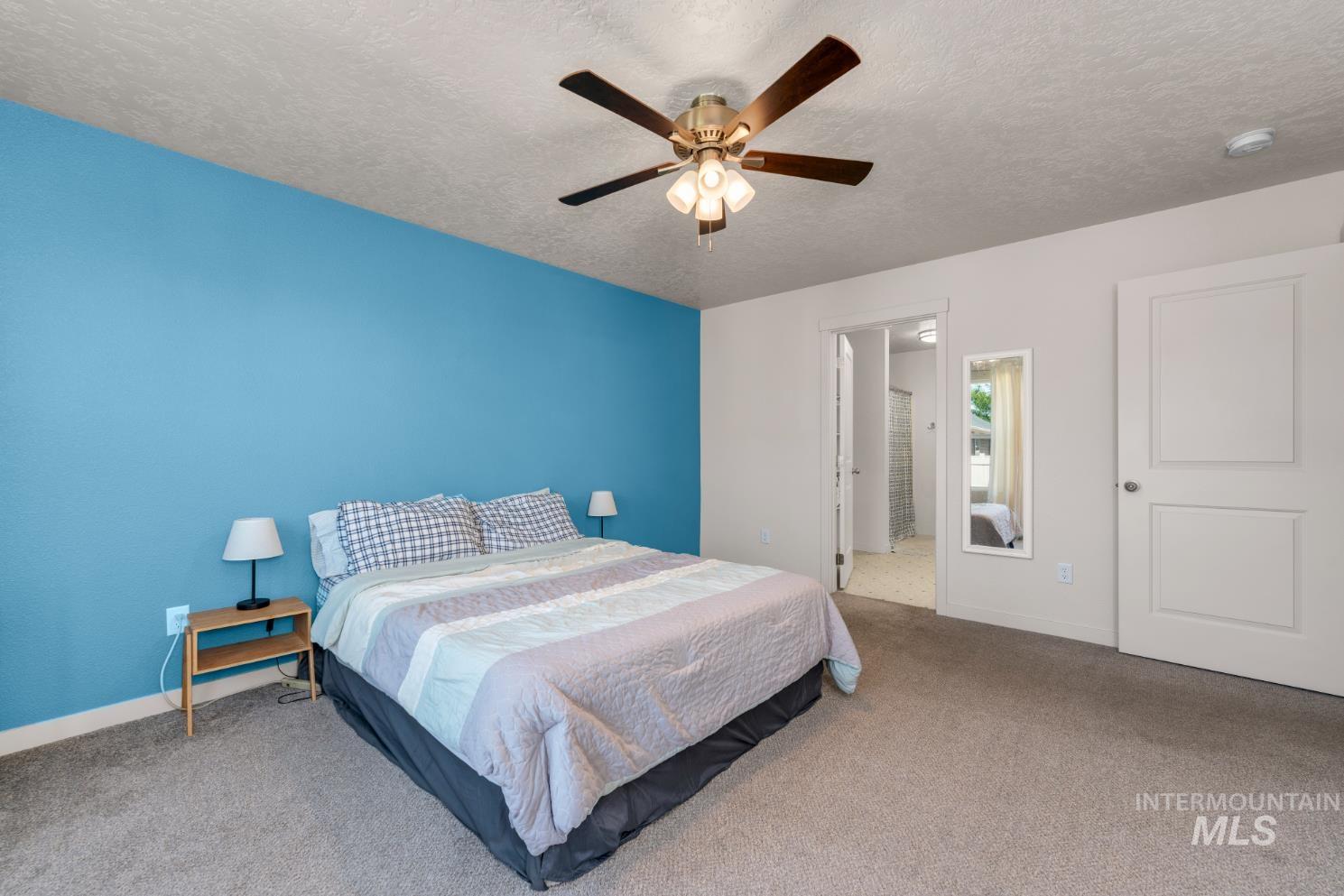 Bedroom featuring carpet flooring, a textured ceiling, a ceiling fan, and ensuite bath