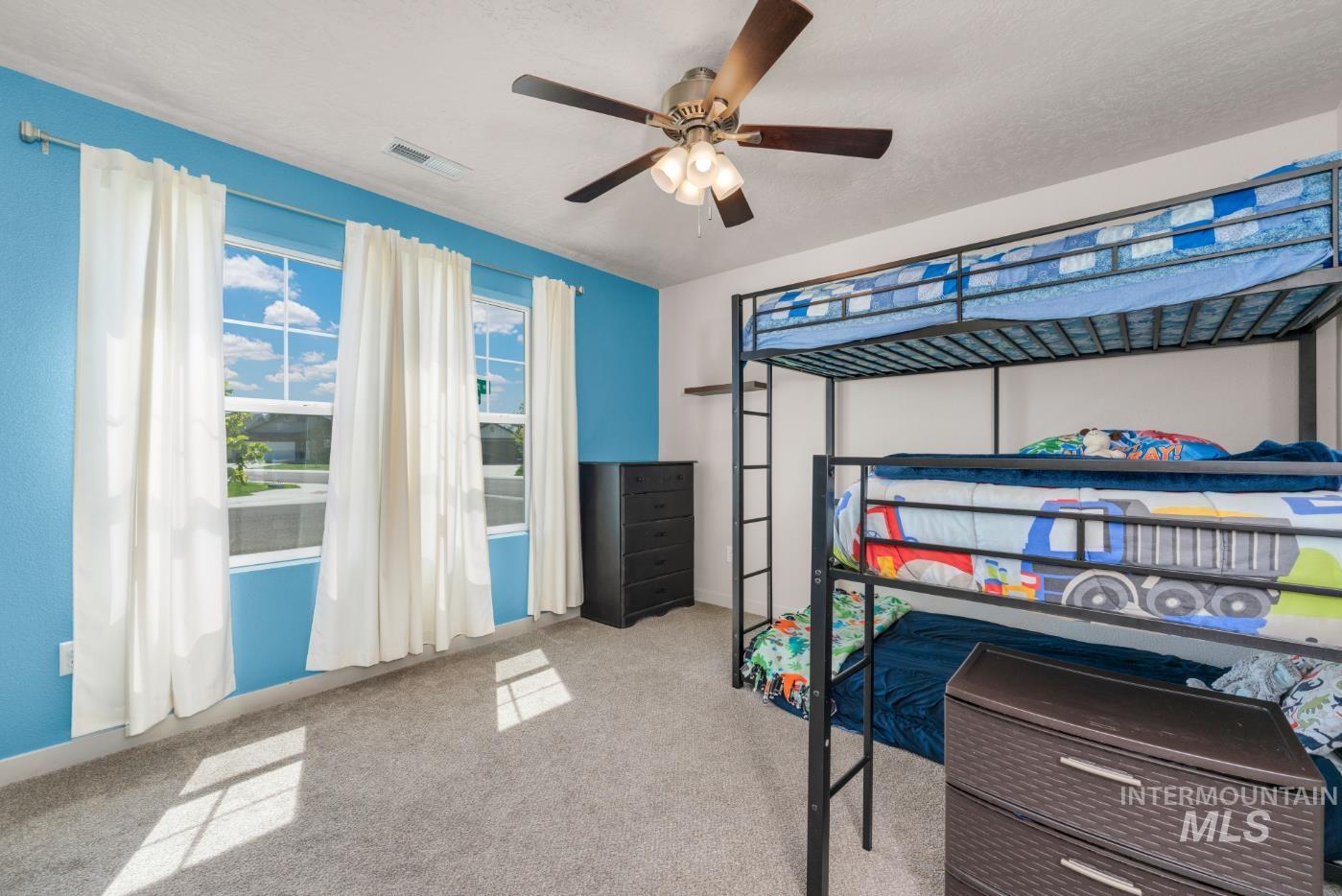 Bedroom with light carpet, ceiling fan, and a textured ceiling
