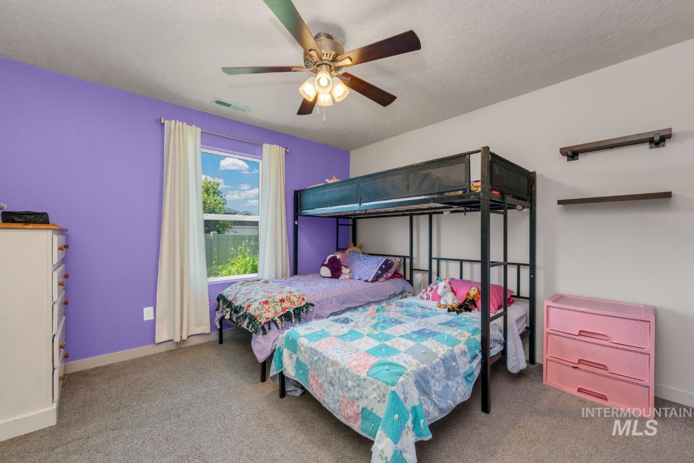 Bedroom with ceiling fan, carpet floors, and a textured ceiling