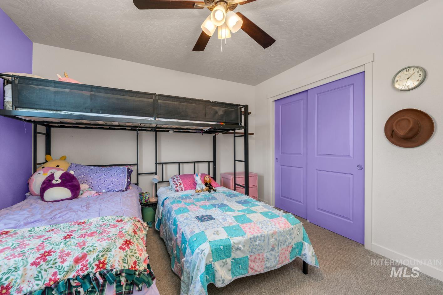Carpeted bedroom with a textured ceiling, a ceiling fan, and a closet