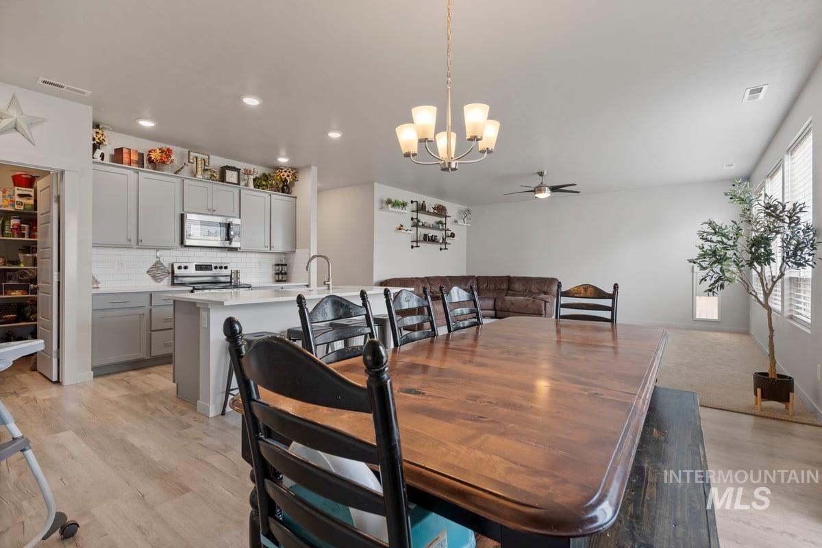 Dining area with ceiling fan, a chandelier, light wood-type flooring, and recessed lighting