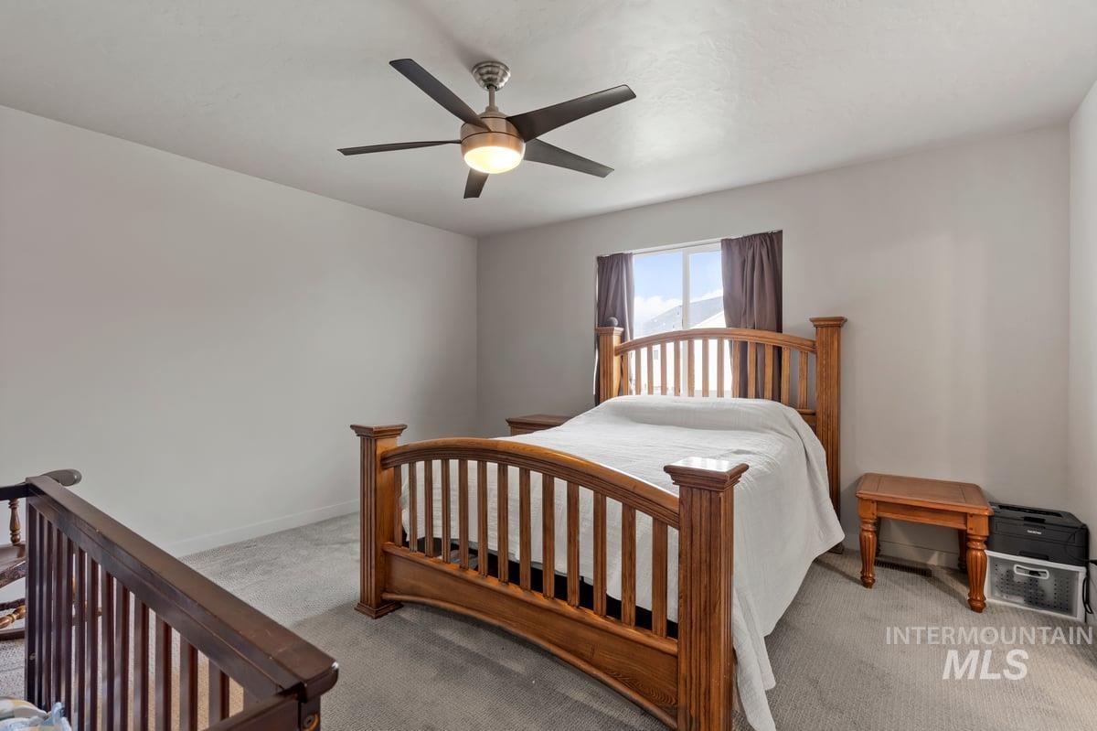 Carpeted bedroom featuring ceiling fan and baseboards
