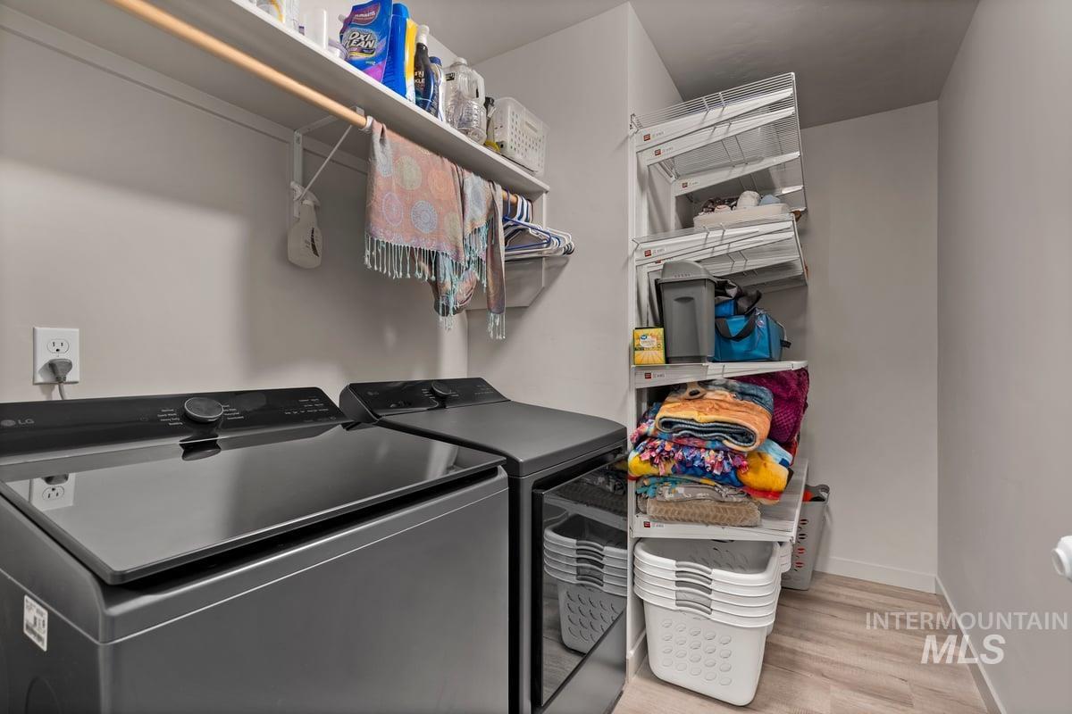 Washroom featuring light wood-type flooring and washing machine and clothes dryer