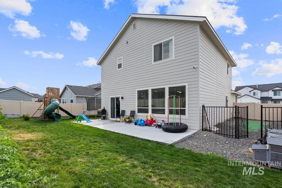 Rear view of house with a patio area, a playground, and a fenced backyard