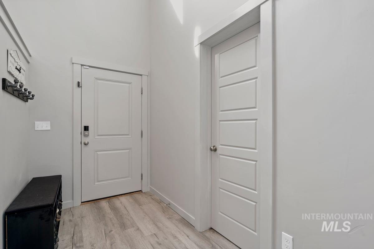 Doorway with wood finished floors and baseboards