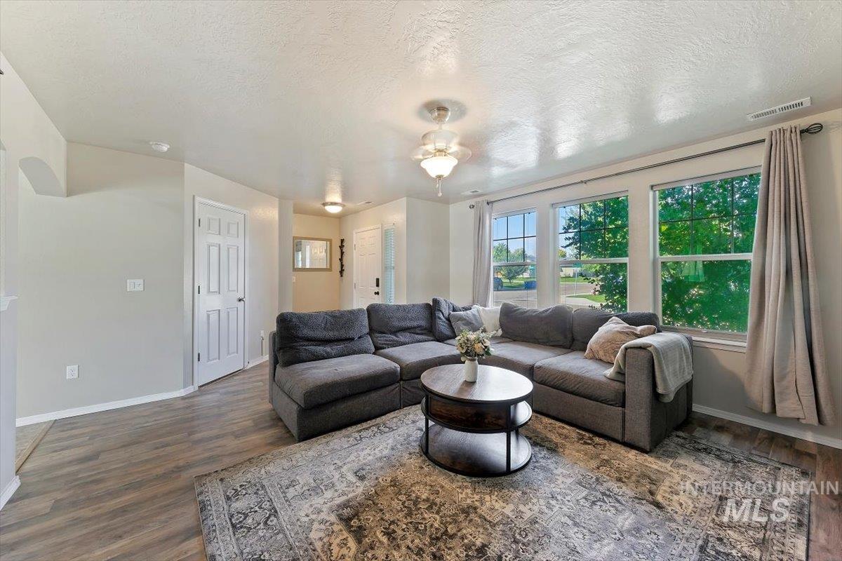 Living area with a textured ceiling, wood finished floors, and arched walkways