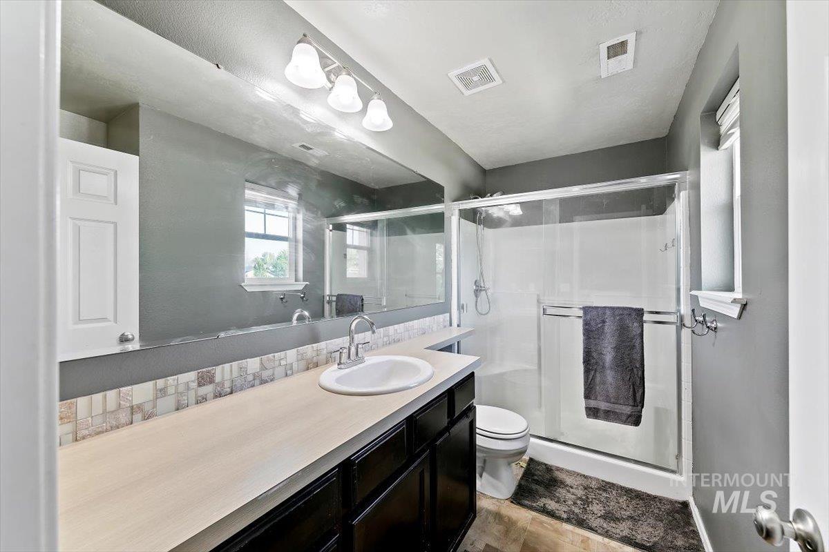 Master Bathroom featuring vanity, a shower stall, and a textured wall