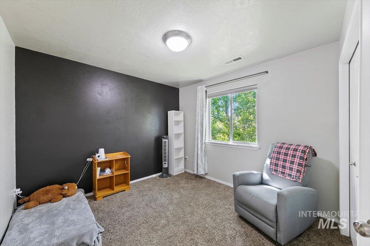 Carpeted bedroom featuring a textured ceiling and a textured wall