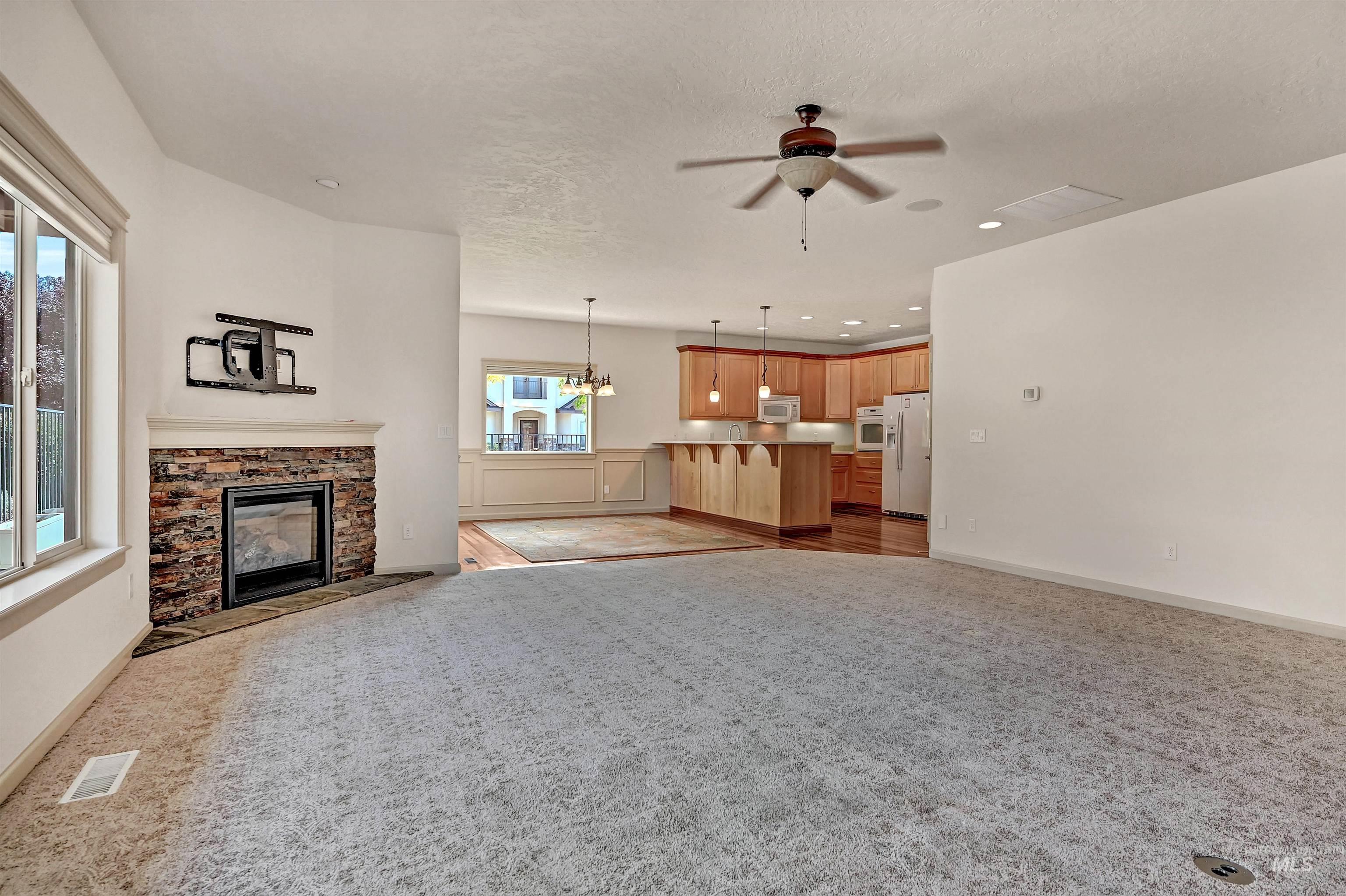 Unfurnished living room with a chandelier, a stone fireplace, recessed lighting, a textured ceiling, and a ceiling fan