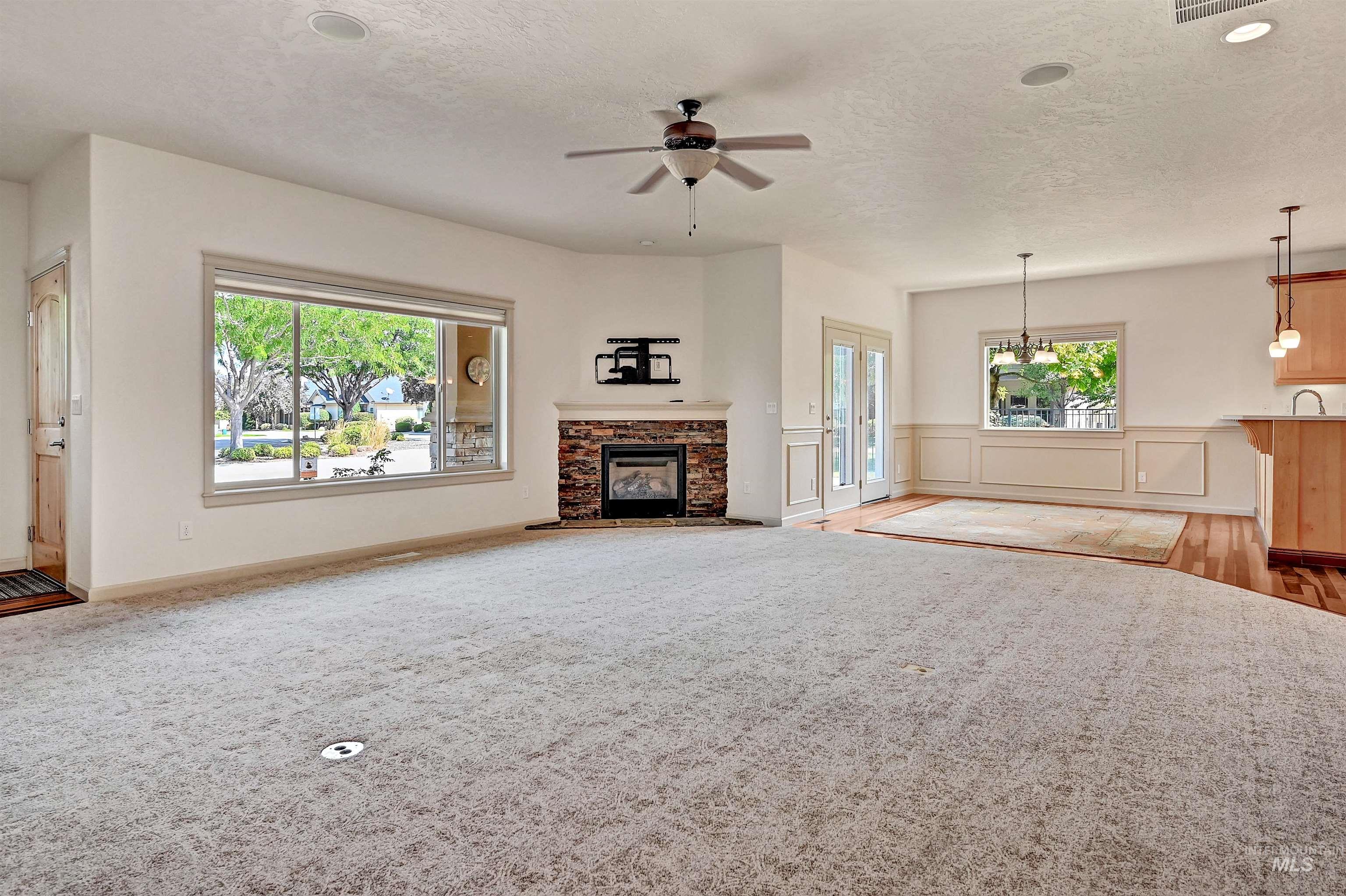 Unfurnished living room with a fireplace, ceiling fan, a textured ceiling, and light carpet