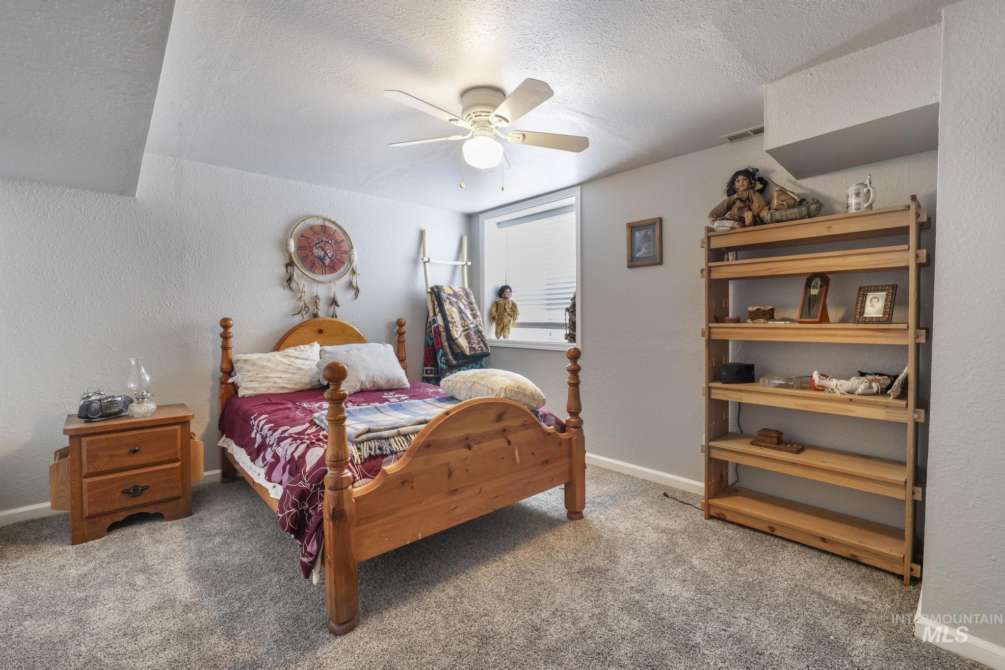 Bedroom with a textured wall, light carpet, a textured ceiling, and ceiling fan